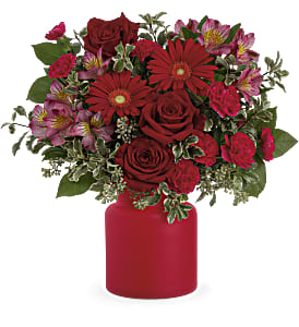 Red roses and pink flowers in a red vase