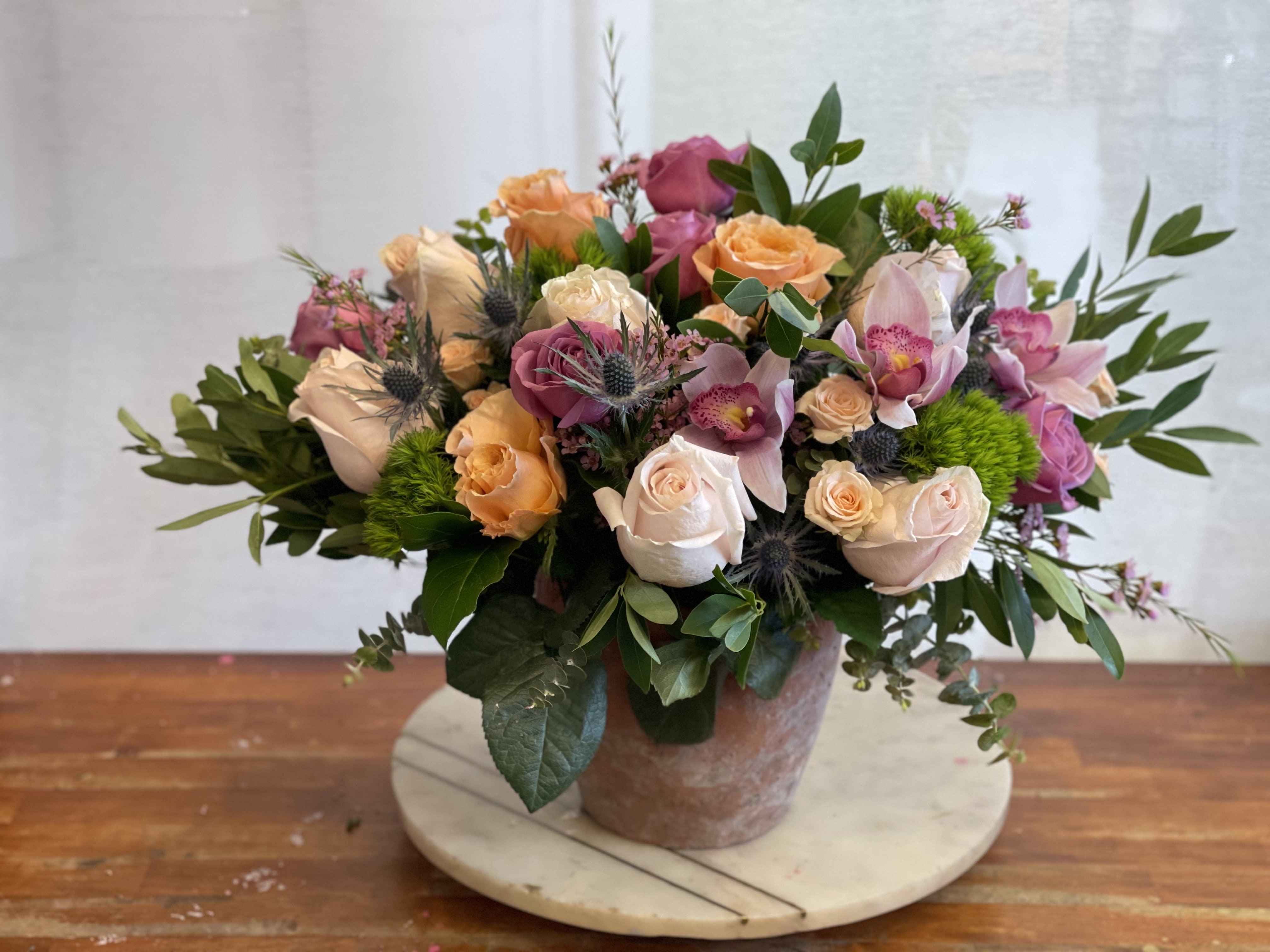 Mixed bouquet of roses and orchids in a ceramic vase
