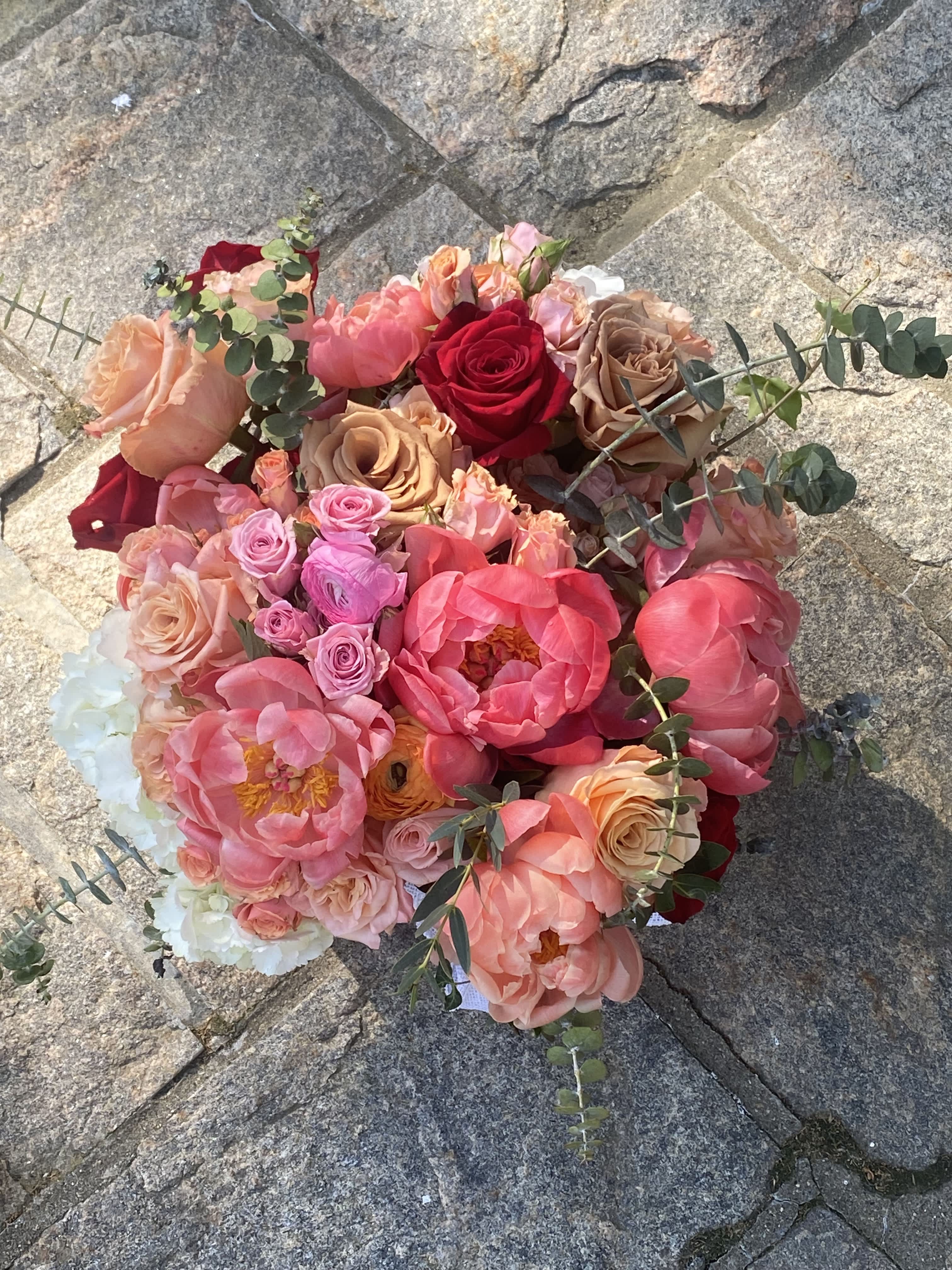 Round bouquet of pink, peach, and red flowers with eucalyptus