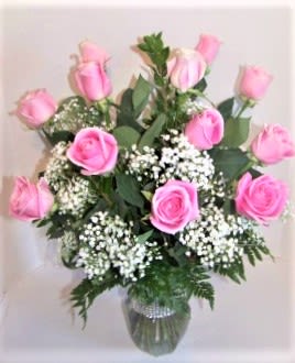 Pink roses arranged in a clear glass vase with white filler flowers