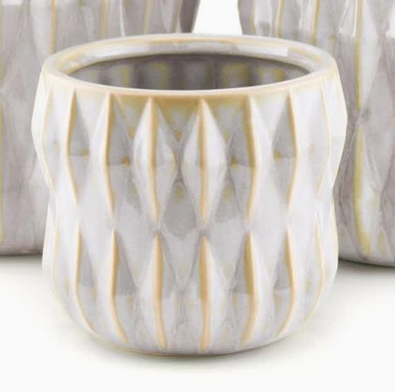 White and gold patterned ceramic vase on a light surface