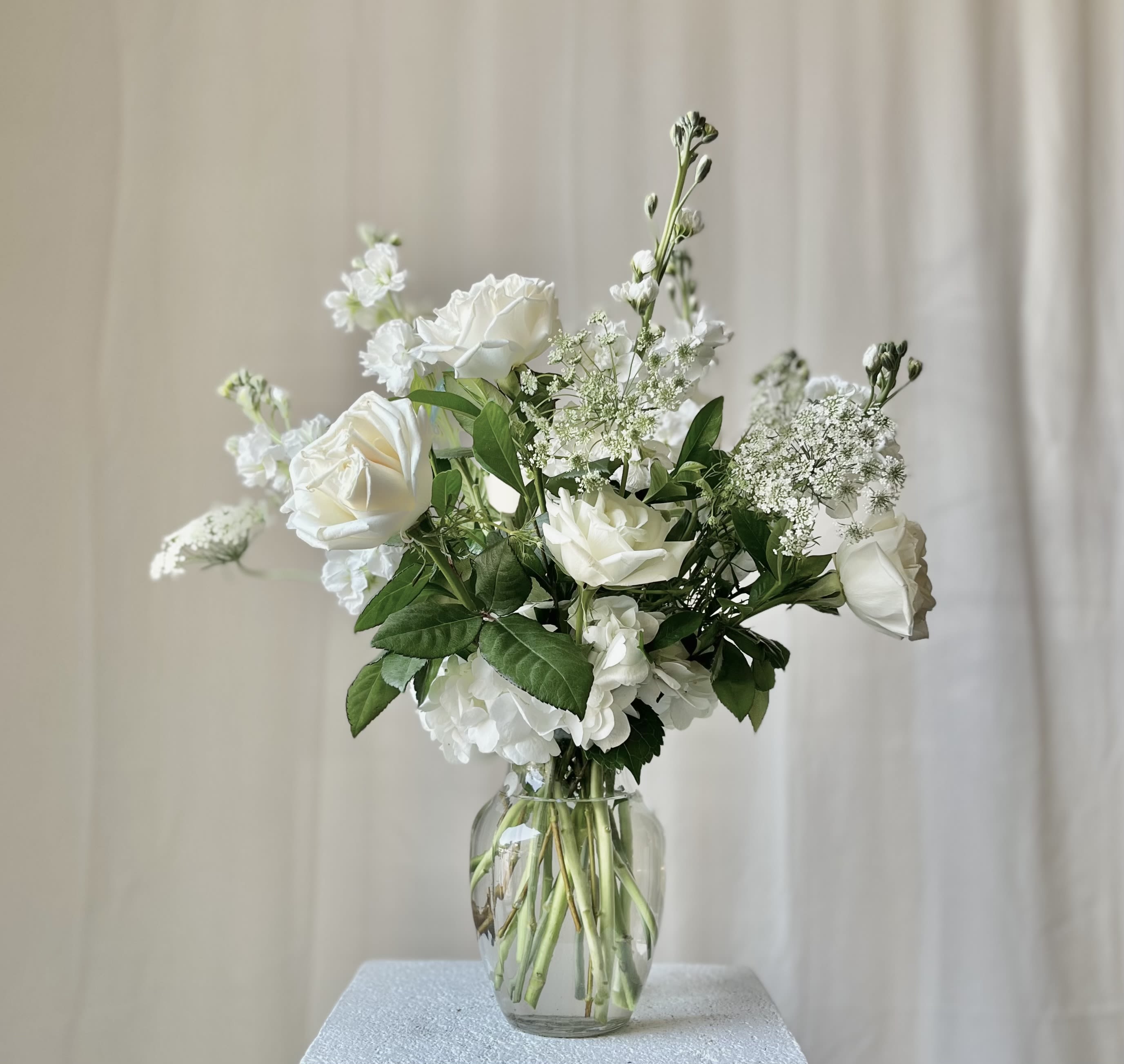 White roses and filler flowers in a clear glass vase