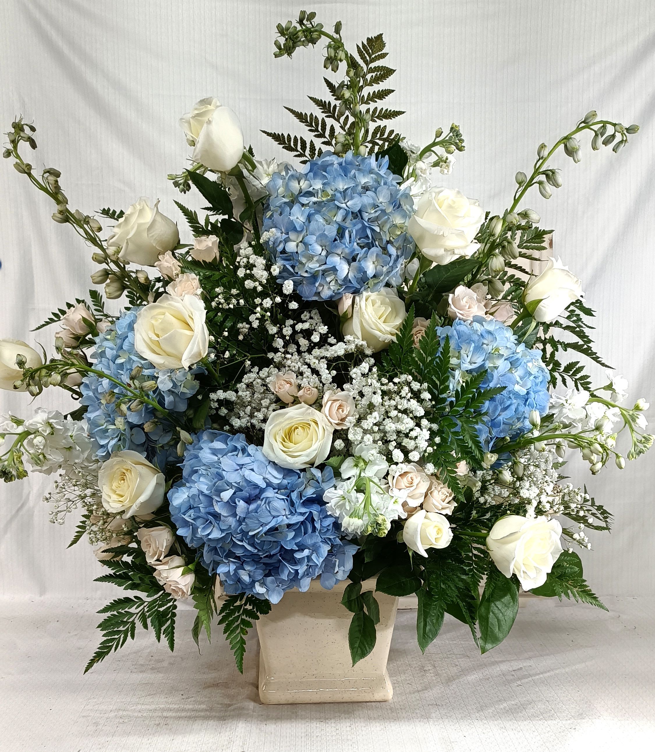 Blue hydrangeas and white roses in a cream vase