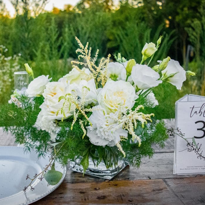 White floral centerpiece in a clear glass vase on a table