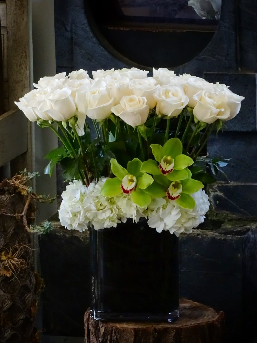 White roses and green orchids in a black vase