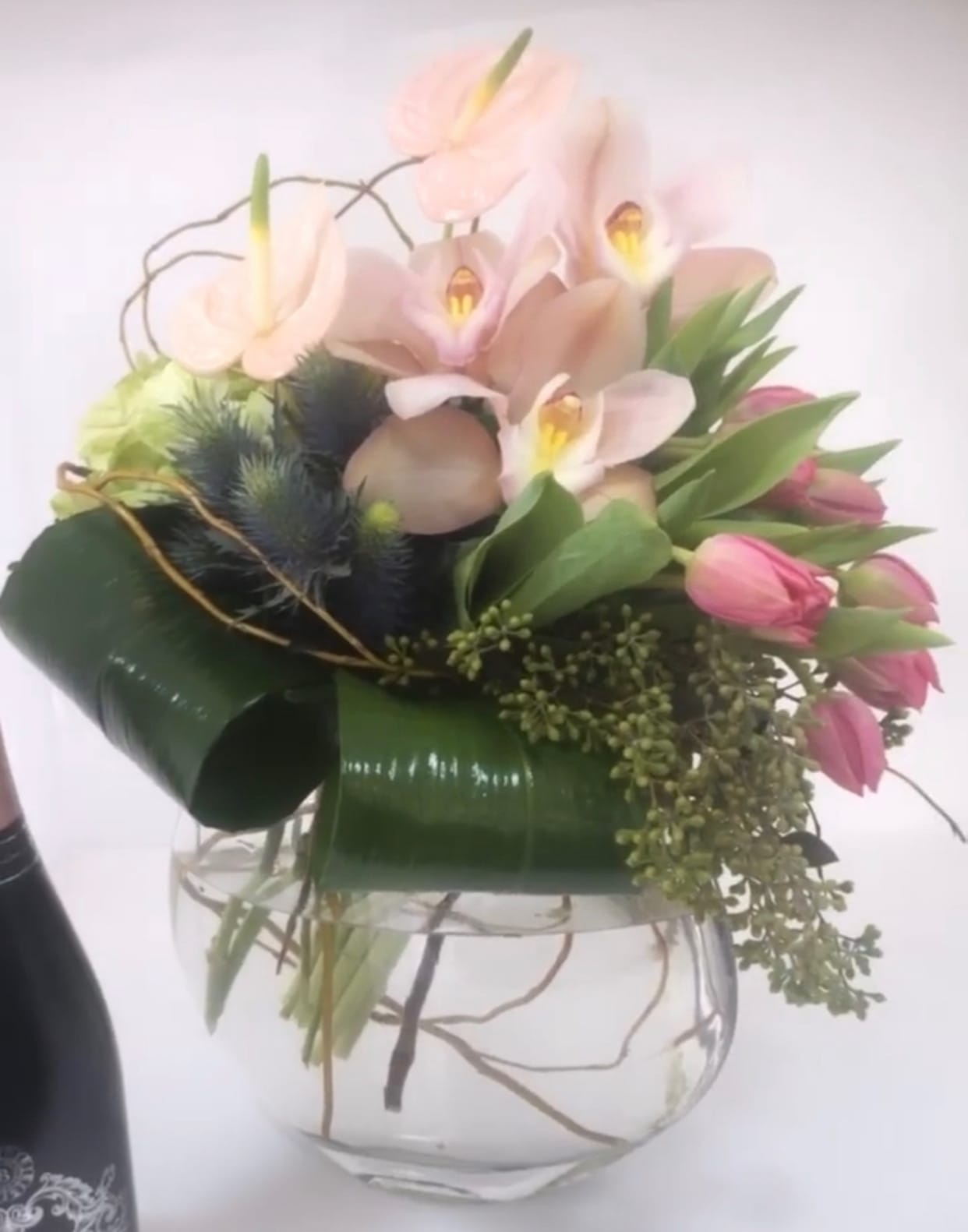 Pink anthuriums and tulips arranged in a clear glass vase