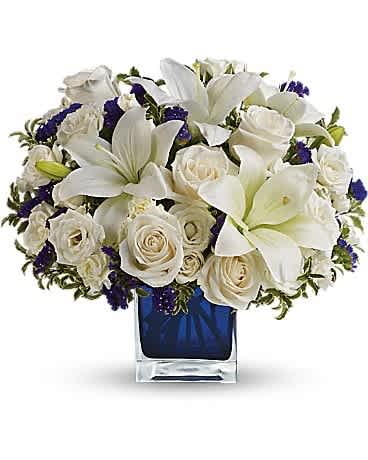 White lilies and roses arranged in a blue glass vase
