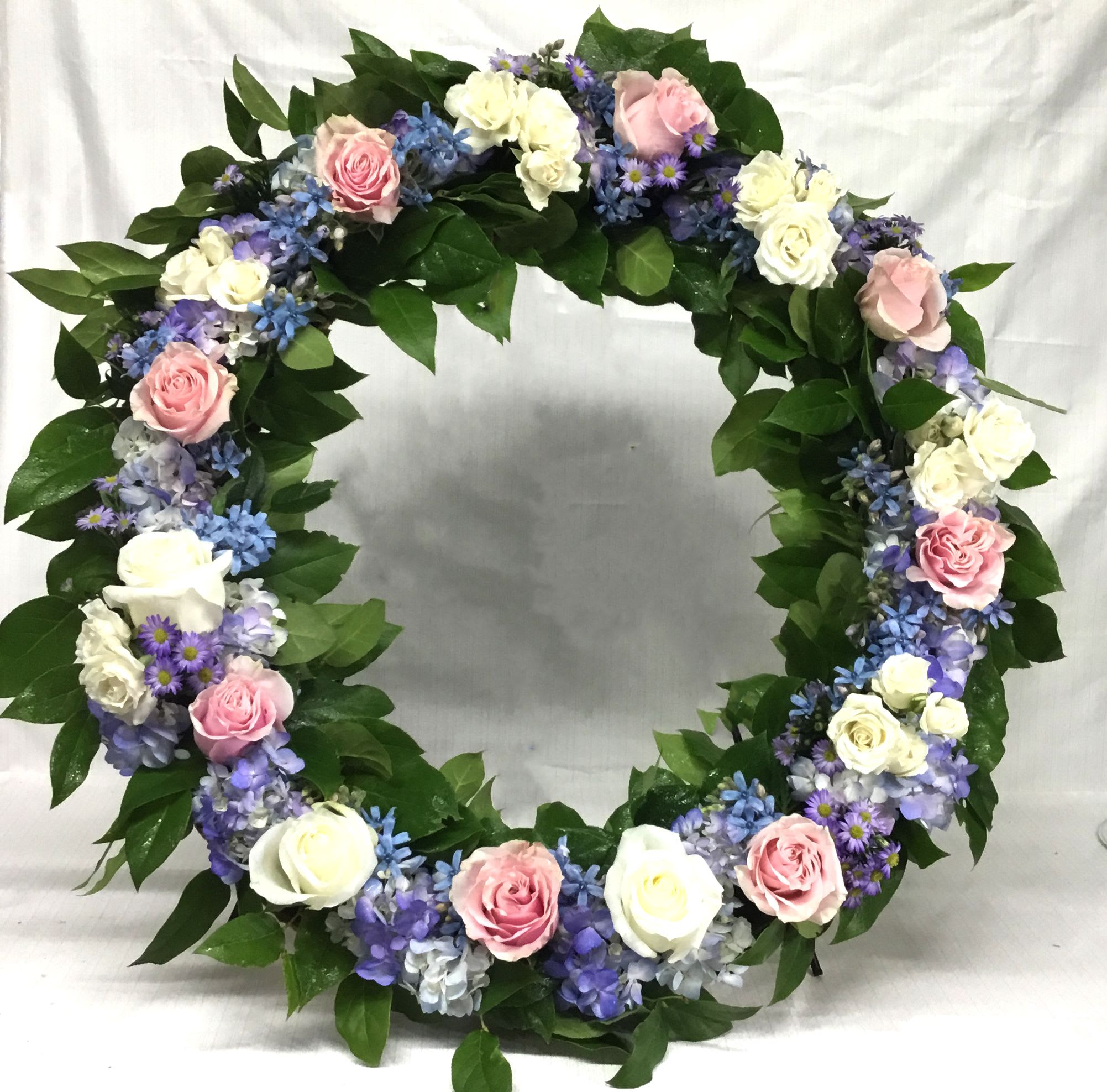 Circular floral wreath with pink and white roses and purple flowers