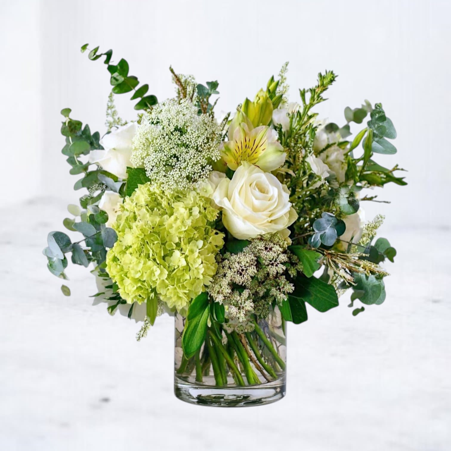 White and green floral arrangement in a clear glass vase