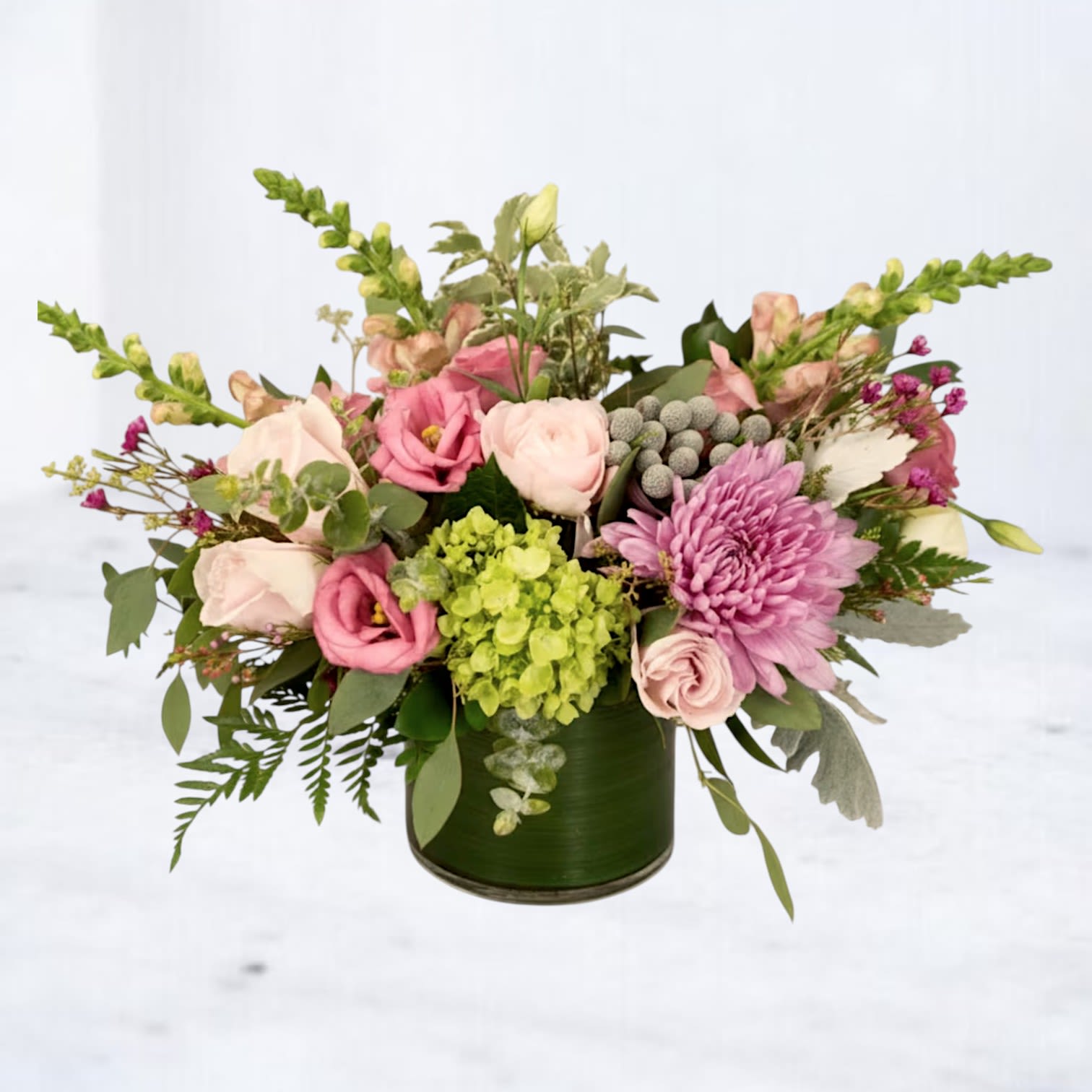 Garden Note - Garden Note is a fresh, garden-inspired floral arrangement designed with soft texture, natural movement, and a calming, organic palette. Featuring blush roses, soft pink blooms, vibrant green hydrangea, and seasonal accent flowers, this arrangement is layered with lush greenery to create a balanced, airy composition.  Designed in a modern green glass vessel, Garden Note blends soft pastels with fresh green tones for a look that feels both serene and refined. The mix of delicate blooms and natural elements gives this arrangement a relaxed, design-forward feel that stands out from traditional floral styles.  Perfect for birthdays, new baby celebrations, sympathy flowers, thank-you gifts, or simply bringing a touch of nature indoors, this garden-style flower arrangement offers a soft, elevated aesthetic for any occasion.  Same-day flower delivery is available in Magnolia, TX, The Woodlands, Montgomery, Conroe, Spring, Tomball, and surrounding North Houston areas.  Due to seasonal availability, some blooms may be replaced with similar varieties of equal or greater value to maintain the design’s look and integrity. Your arrangement will always reflect the same color palette, style, and premium quality.