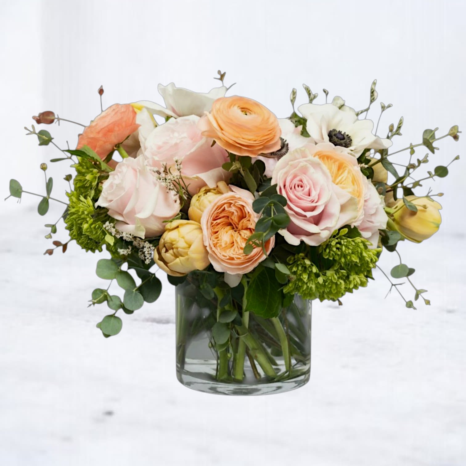 Elysian Bloomscape - Graceful and garden-forward, Elysian Bloomscape captures the beauty of soft color, natural movement, and abundant texture. A harmonious blend of blush, ivory, and fresh greenery creates a full, flowing arrangement with a relaxed yet elevated feel.  Designed with premium seasonal flowers and a generous hand, this piece offers the look of a lush garden gathering—perfect for everyday celebrations, heartfelt thanks, or simply brightening someone’s space.  Flower varieties may vary based on seasonal availability, but overall color palette, style, and fullness will be thoughtfully maintained.