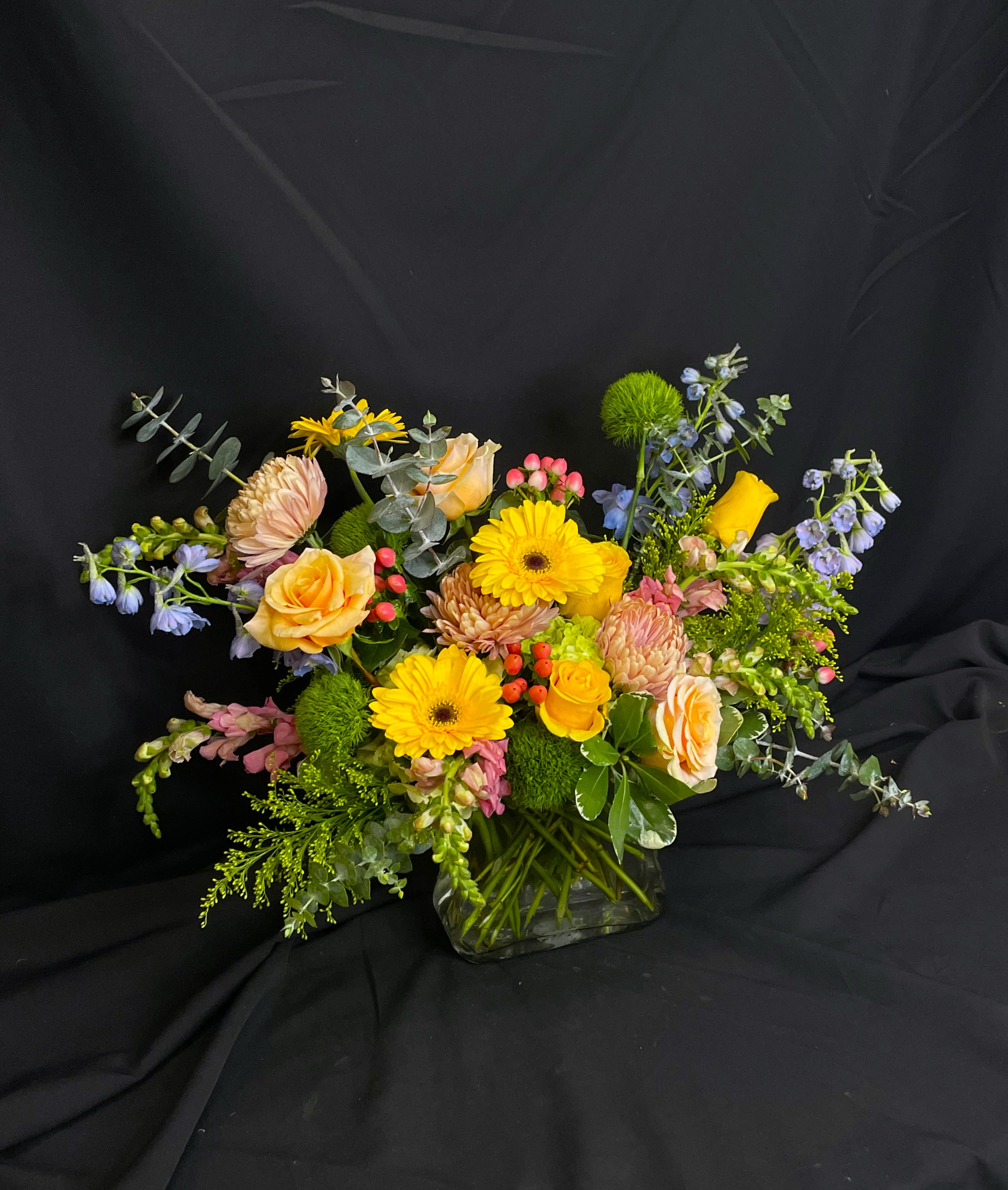 Take Her Shopping - Beautiful spring colors fill a purse shaped clear vase to create a whimsical and garden-y arrangement. Perfect for Mother's Day to show your mom just how special she is! This is a one sided arrangement.