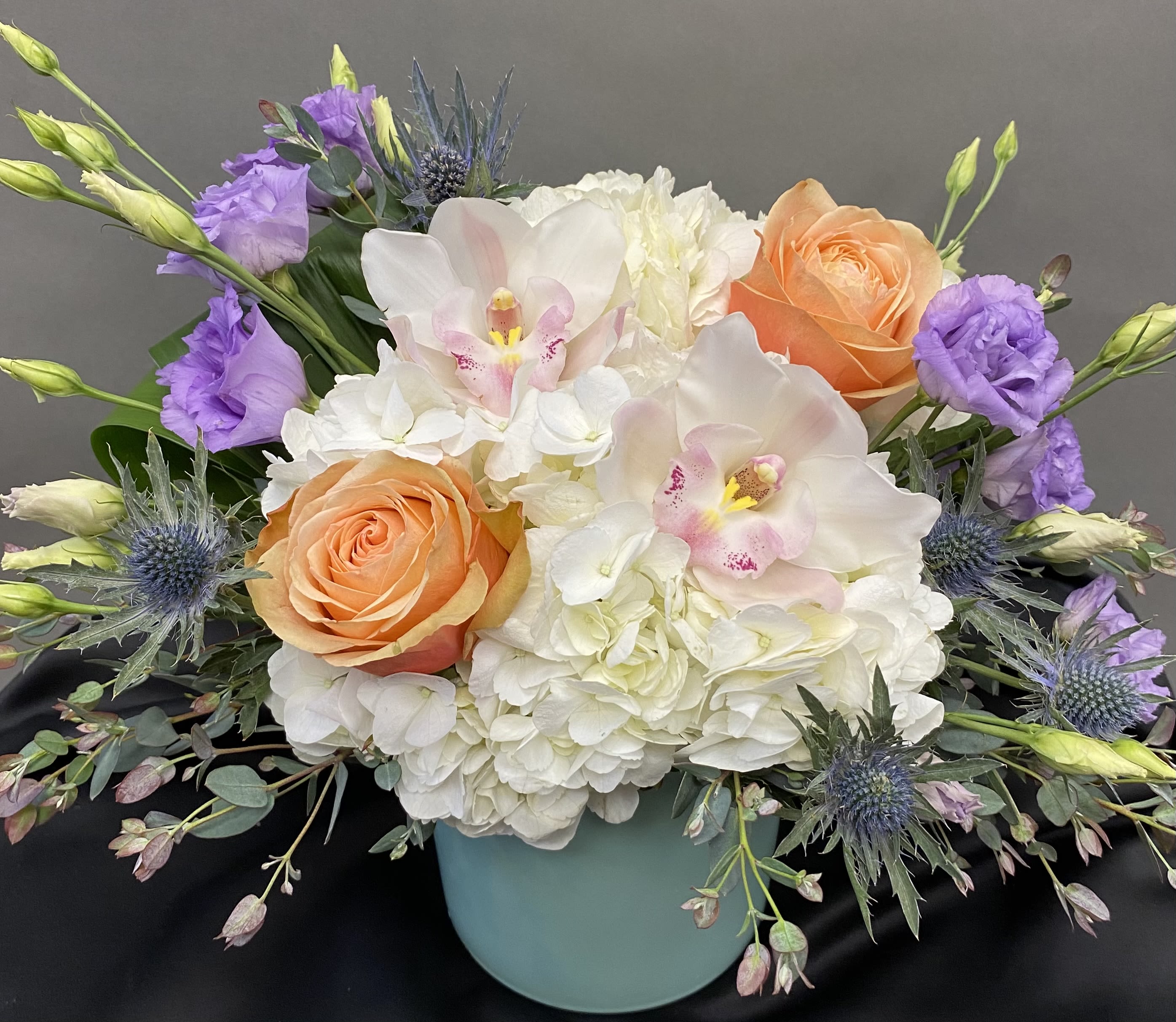Bouquet of white hydrangeas, peach roses, and purple blooms in a blue vase