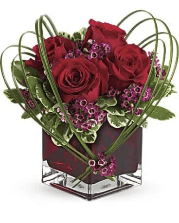 Red roses and purple filler in a square glass vase
