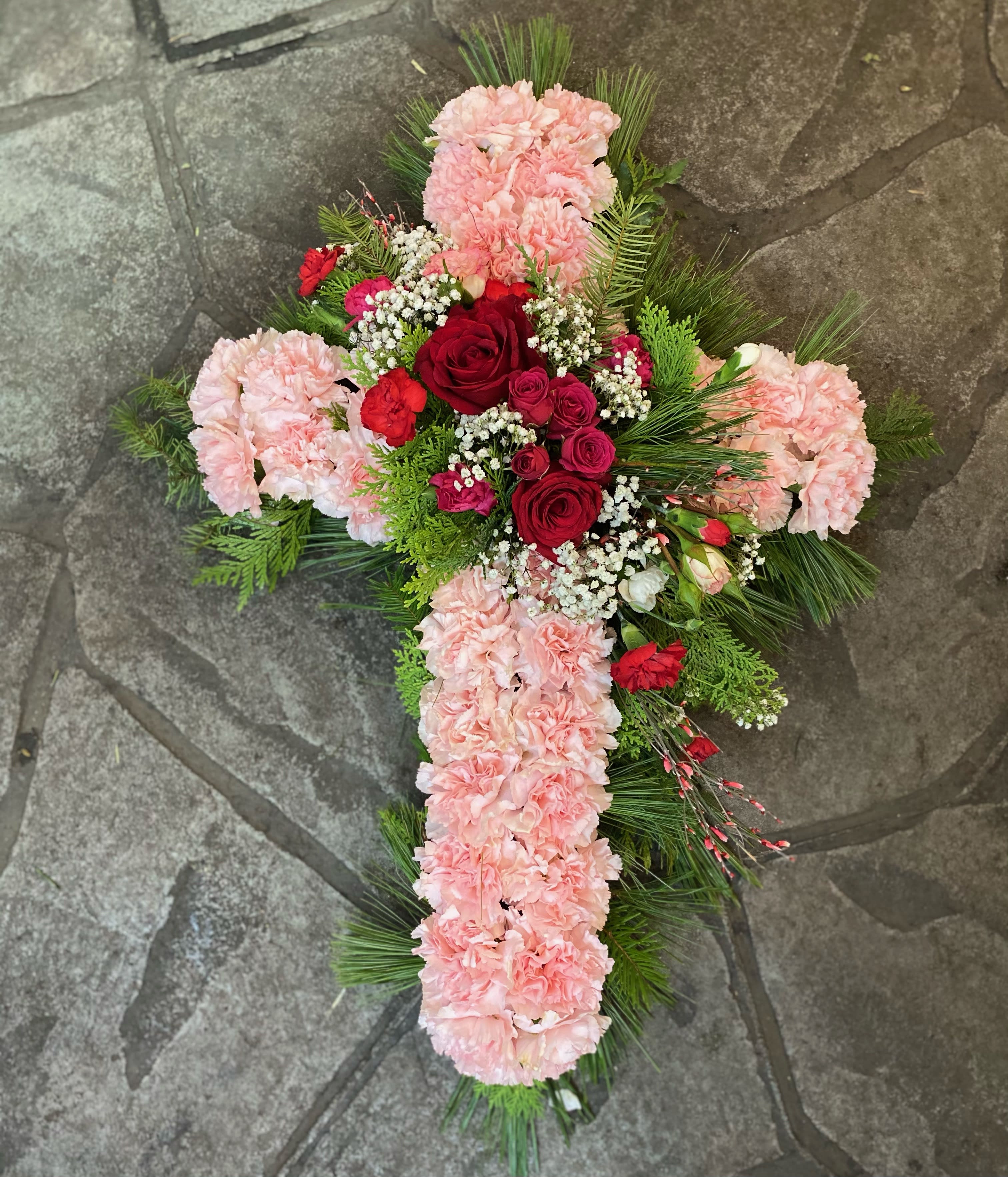 Cross-shaped floral arrangement with pink carnations and red roses