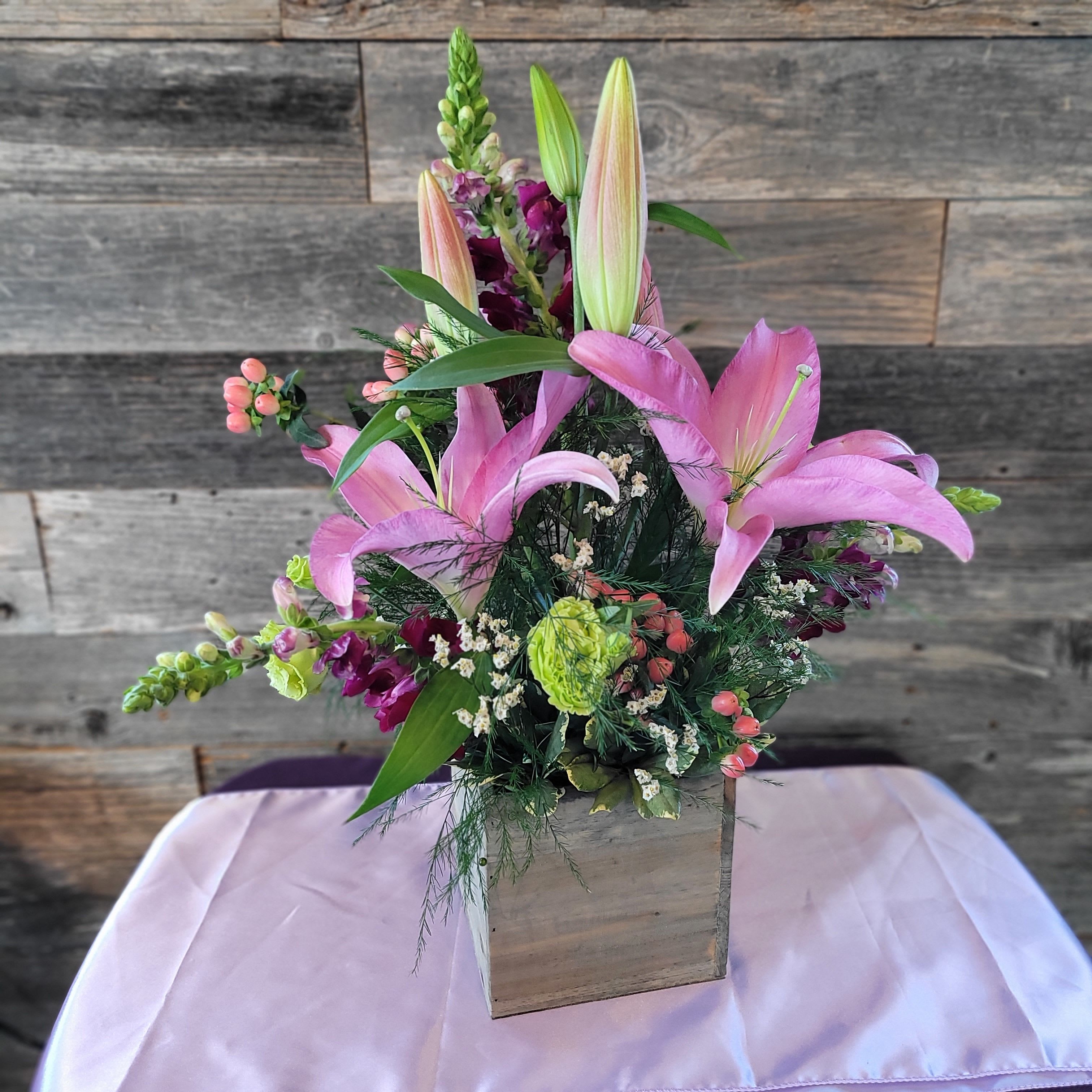 Spring Time - Tall mixed bouquet of pink lilies, purple snapdragons and green  Lisianthus in a square wooden cube vase.