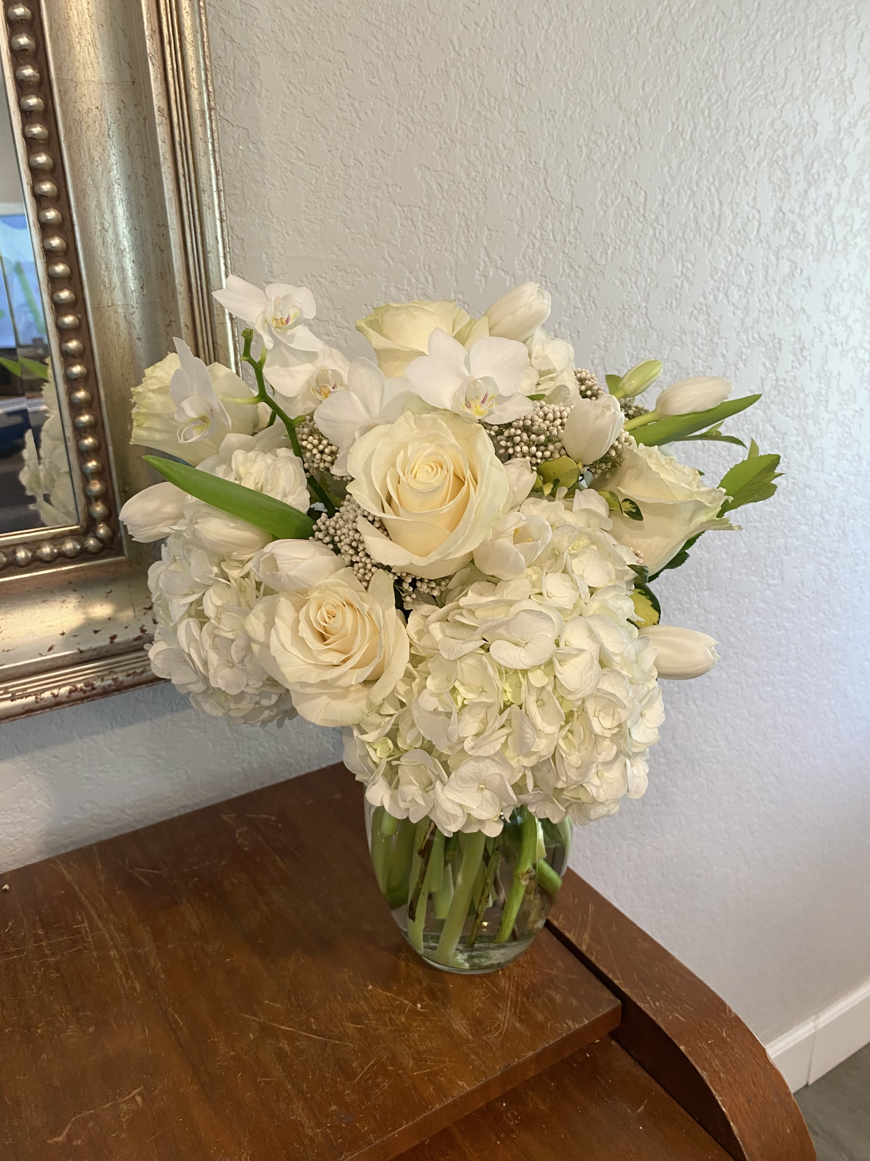 White roses and hydrangeas arranged in a clear glass vase