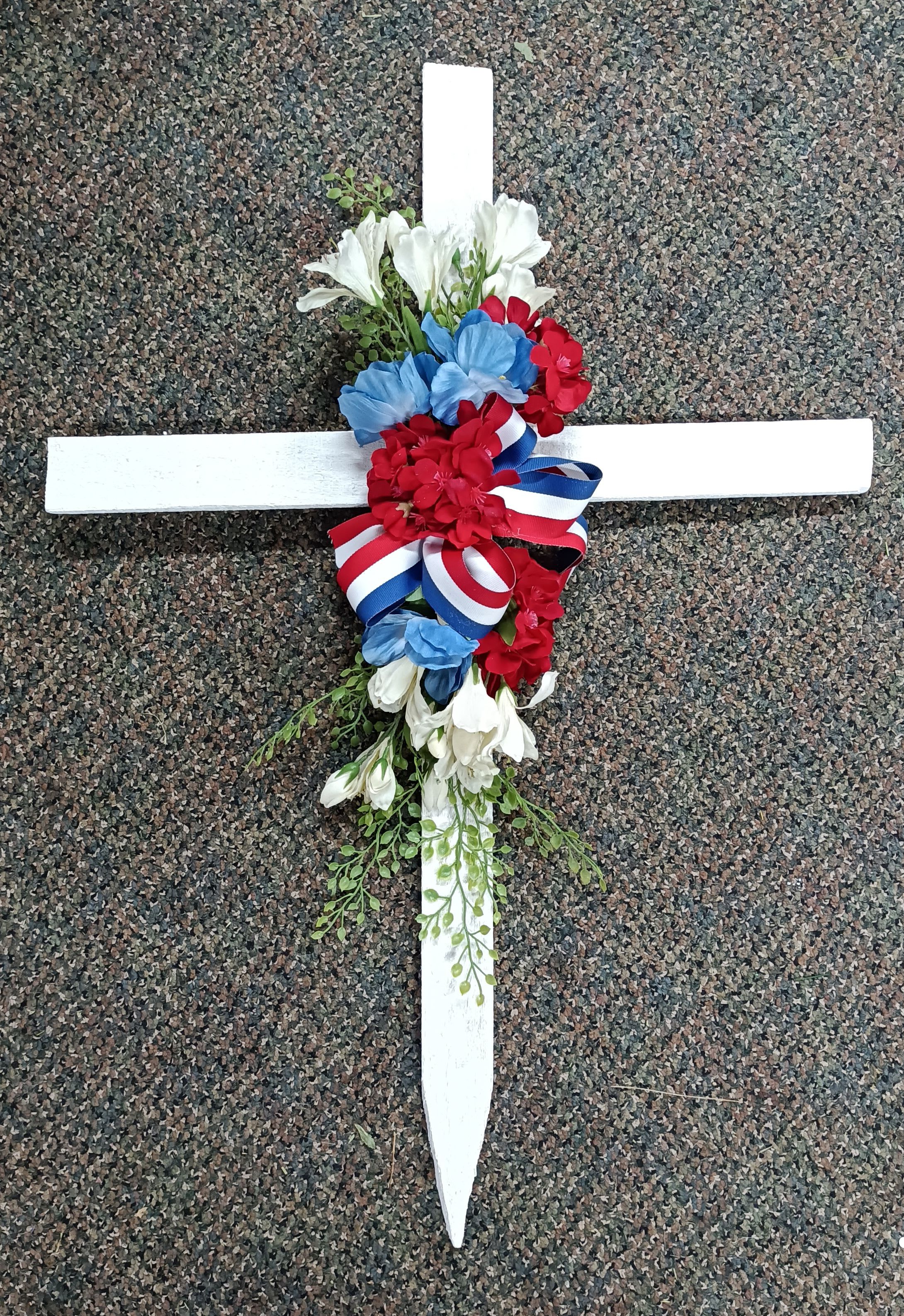Floral cross with red, white, and blue flowers and ribbon