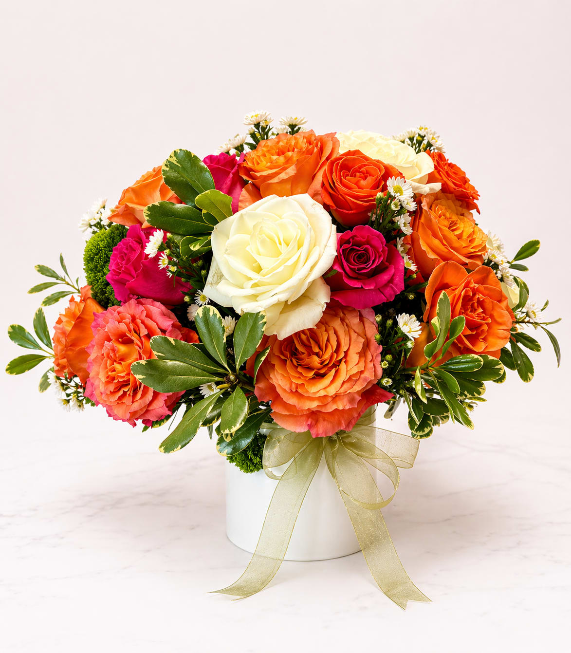 Radiant Bloom Garden - A bold and beautiful blend of ivory, fuchsia, and vibrant orange blooms, designed to make a statement. This lush arrangement combines soft elegance with lively color, creating the perfect balance of warmth and energy. Arranged in a modern ceramic vessel and finished with a delicate ribbon, it’s a joyful, ready-to-gift design for any special moment.