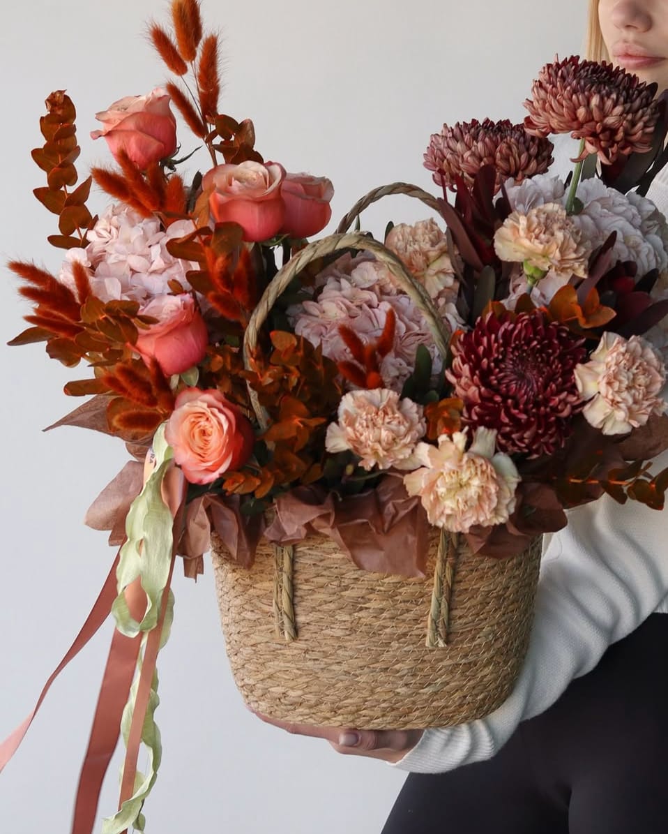 Basket arrangement of pink roses and burgundy chrysanthemums