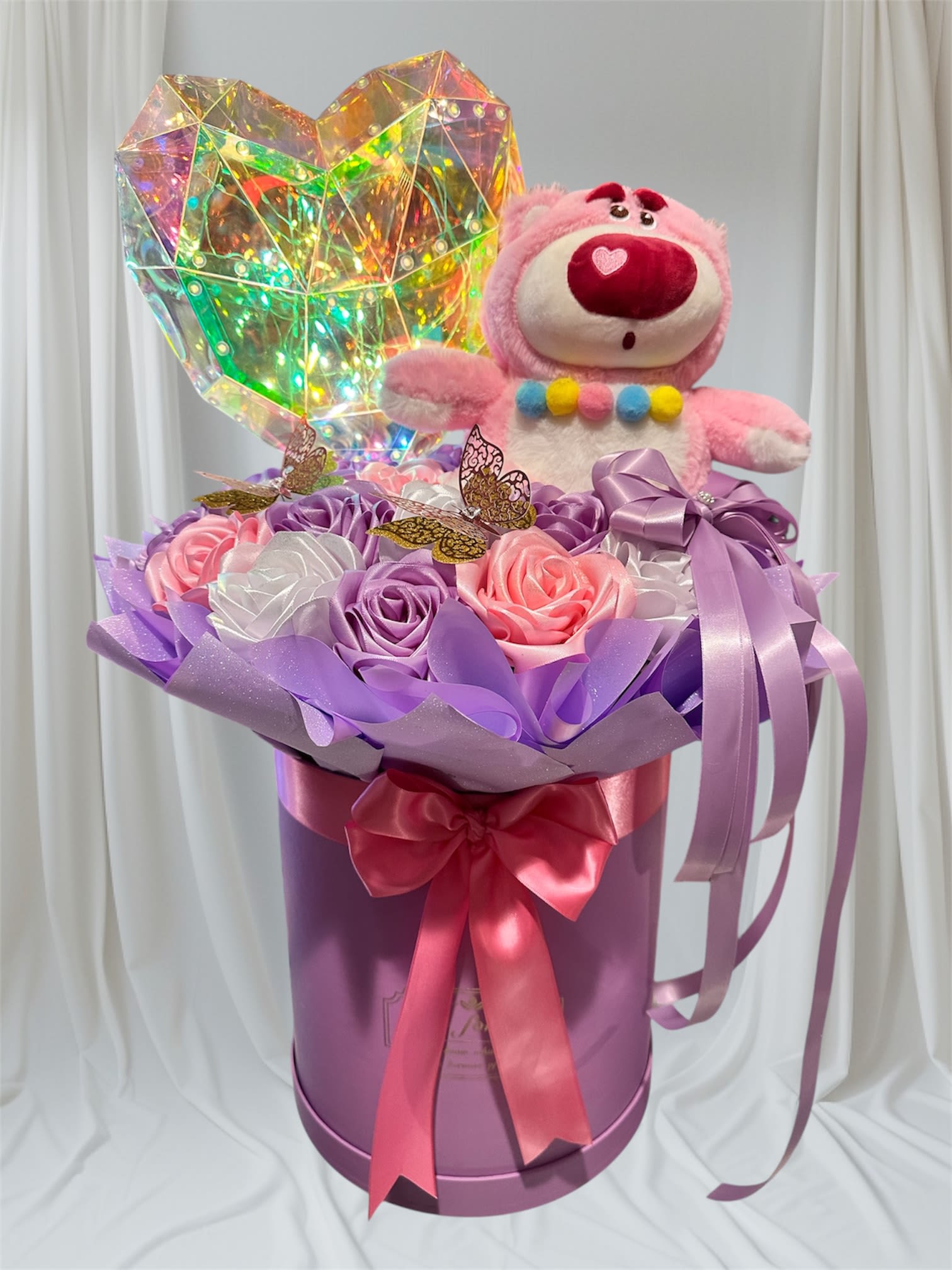 Pink teddy bear in a purple gift box with satin roses and a holographic heart