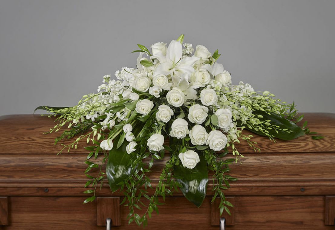 Draped In Love Casket Spray - This tribute creates a serene and comforting display that reflects deep affection and cherished memories. Draped In Love honors a life that was deeply loved and will forever be remembered, offering a beautiful expression of sympathy and farewell.  