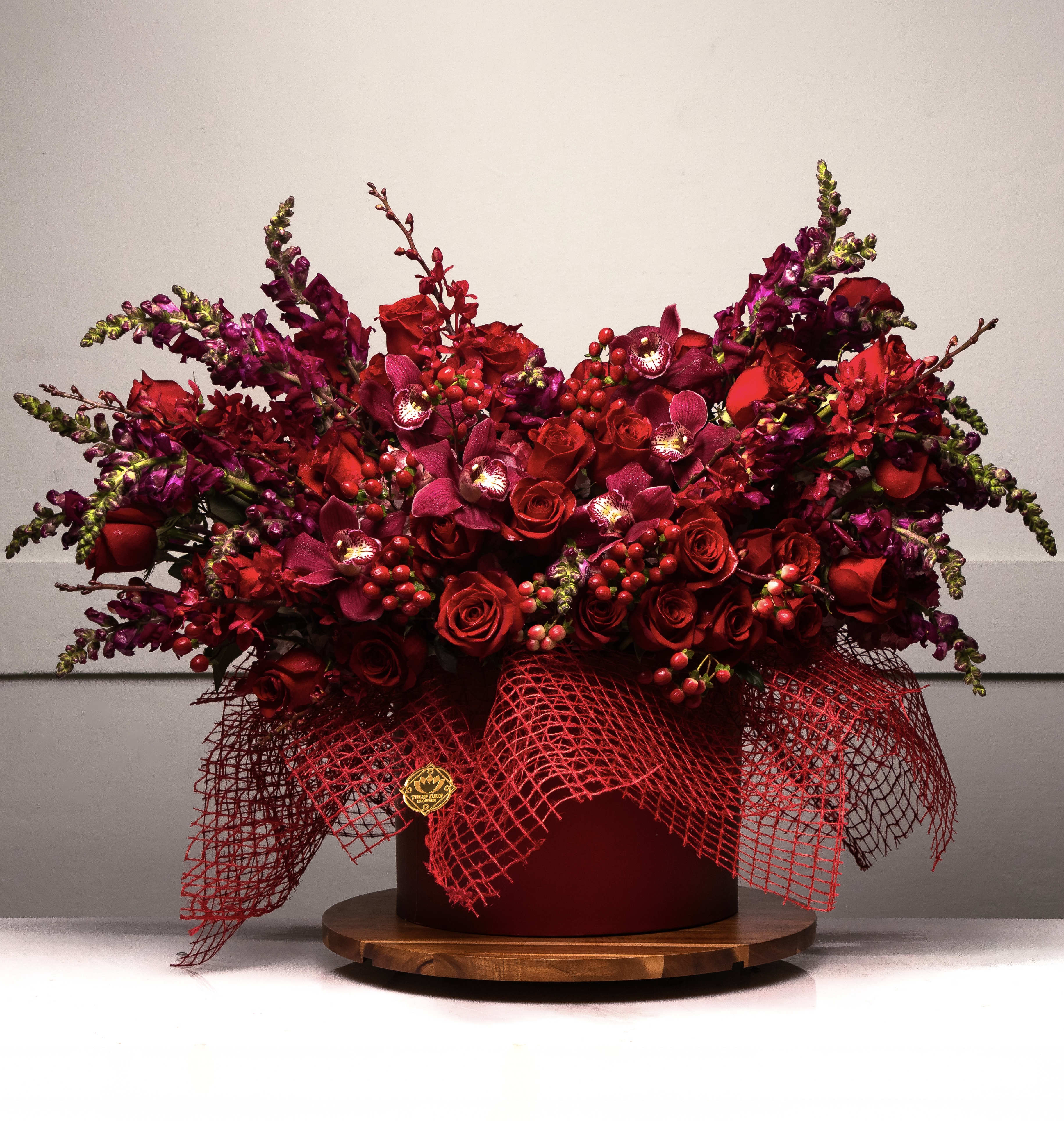 Large red floral arrangement in a round box with mesh wrap