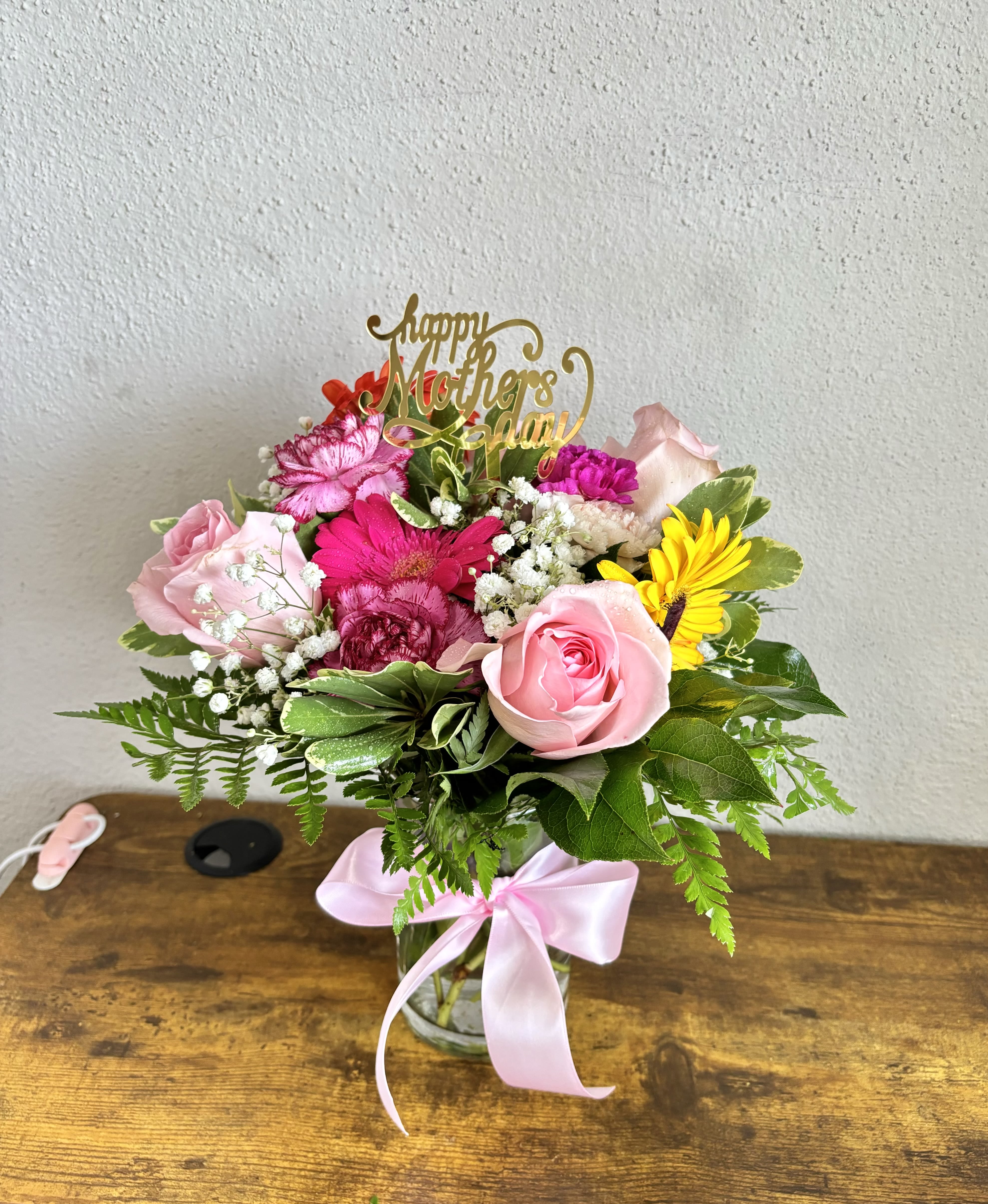 Pink and yellow mixed bouquet in a glass vase with a Mother’s Day topper