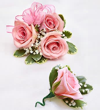 Pink rose corsage and boutonniere with ribbon and small white filler flowers