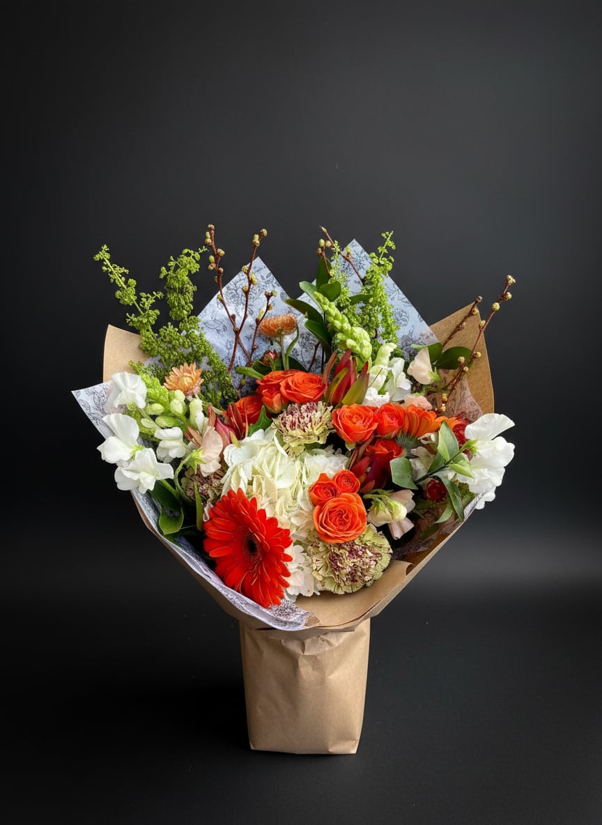 Bouquet of orange, white, and red flowers wrapped in brown paper