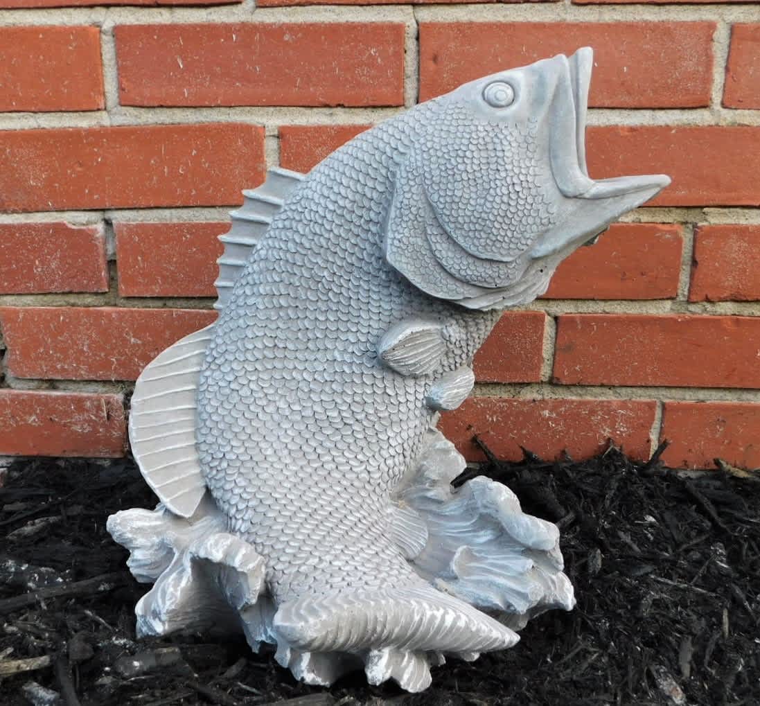 Silver fish sculpture against a brick wall