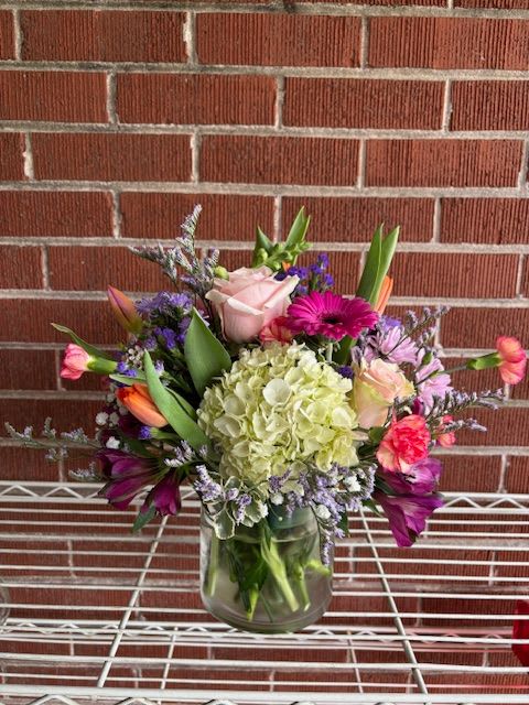 Mixed bouquet in a glass vase with pink, purple, and green flowers