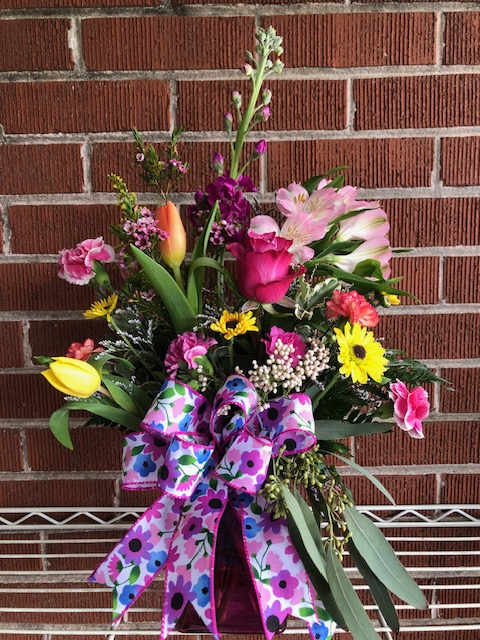 Colorful mixed flower arrangement with a large patterned ribbon