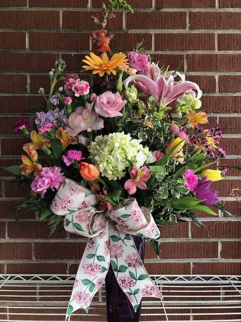 Large mixed flower arrangement with a floral ribbon bow