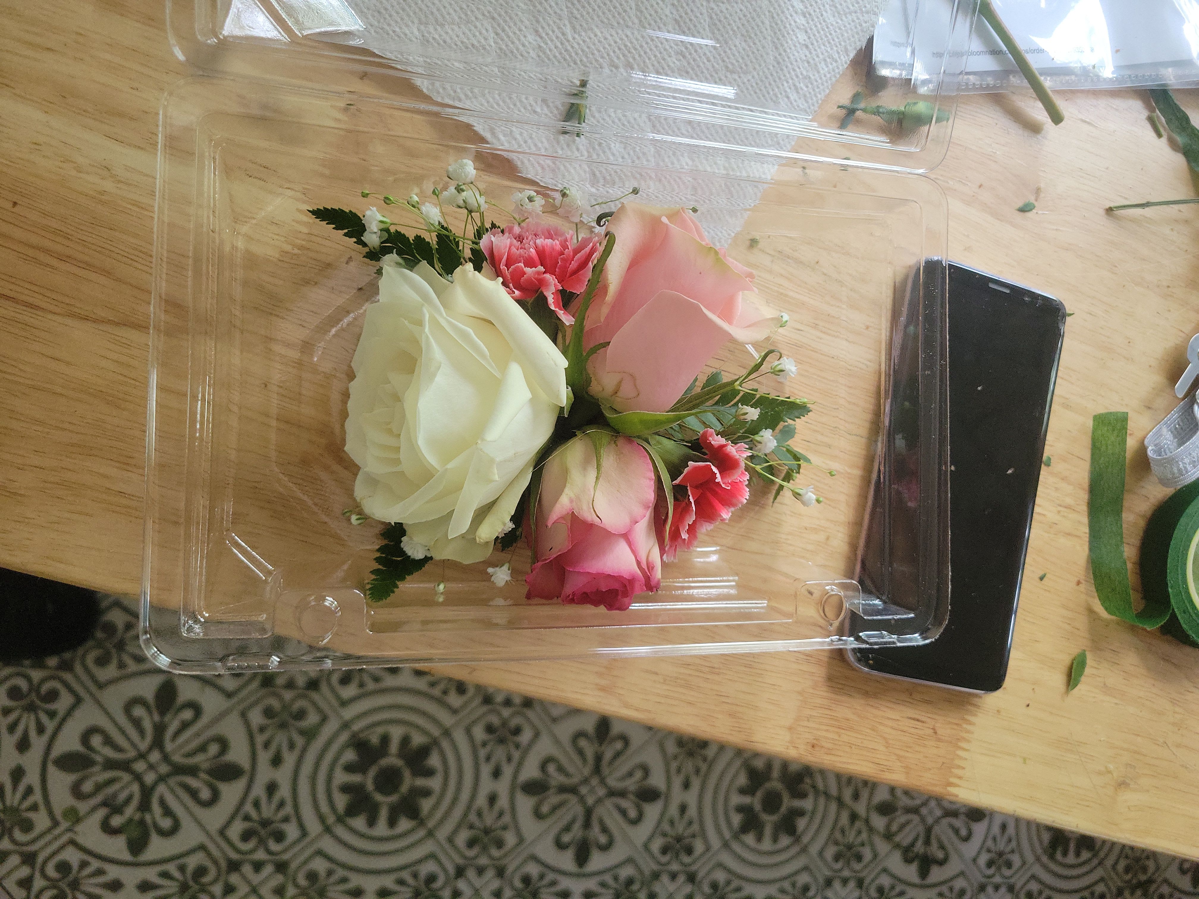 Small bouquet of pink and white roses in a clear plastic box