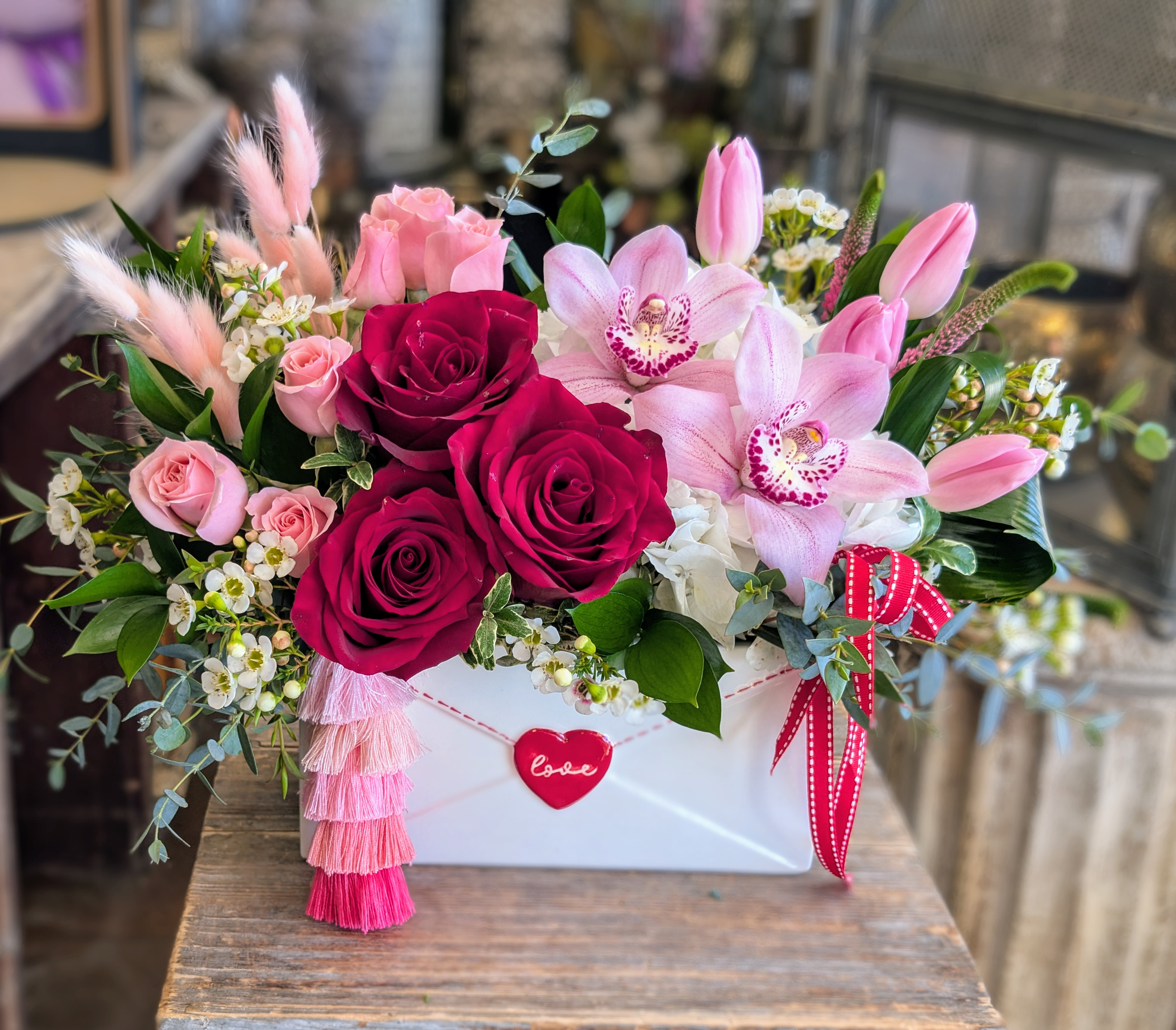 Pink and red rose arrangement with orchids in a white box