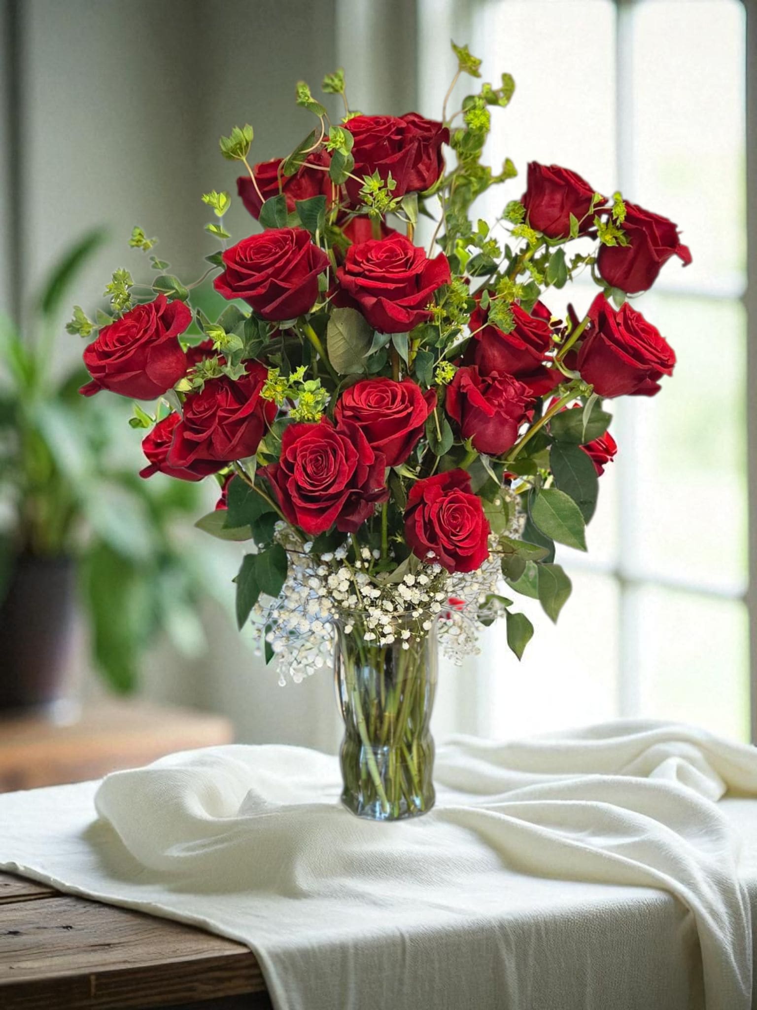Red roses arranged in a clear glass vase with baby's breath