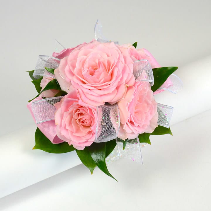 Pink rose corsage with sparkly sheer ribbon on a white background