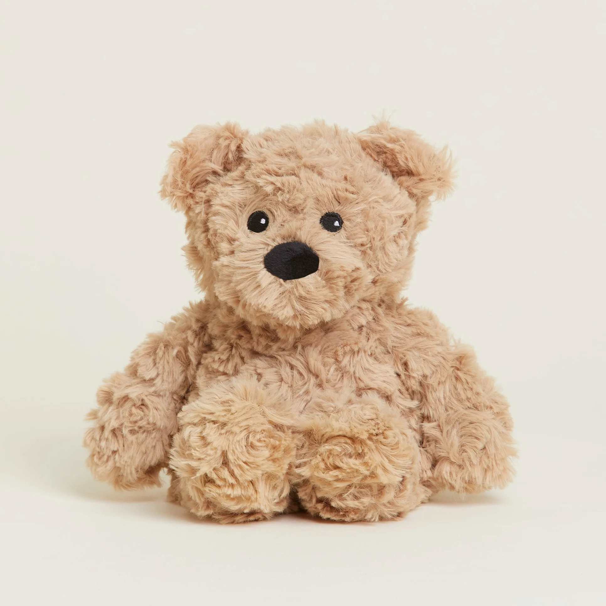 Small tan plush teddy bear sitting upright on a light background
