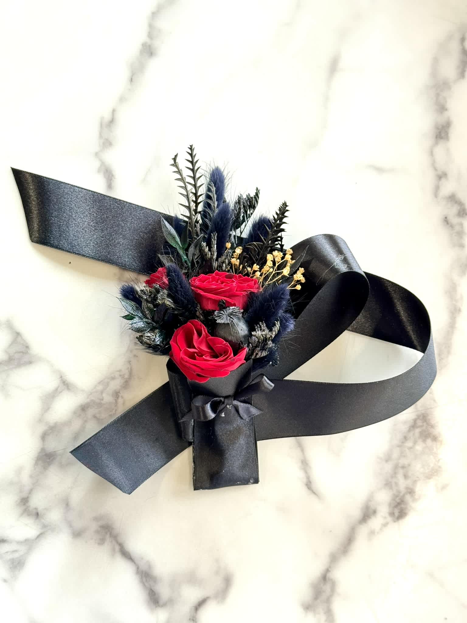 Small bouquet of red roses with black ribbon on a marble surface