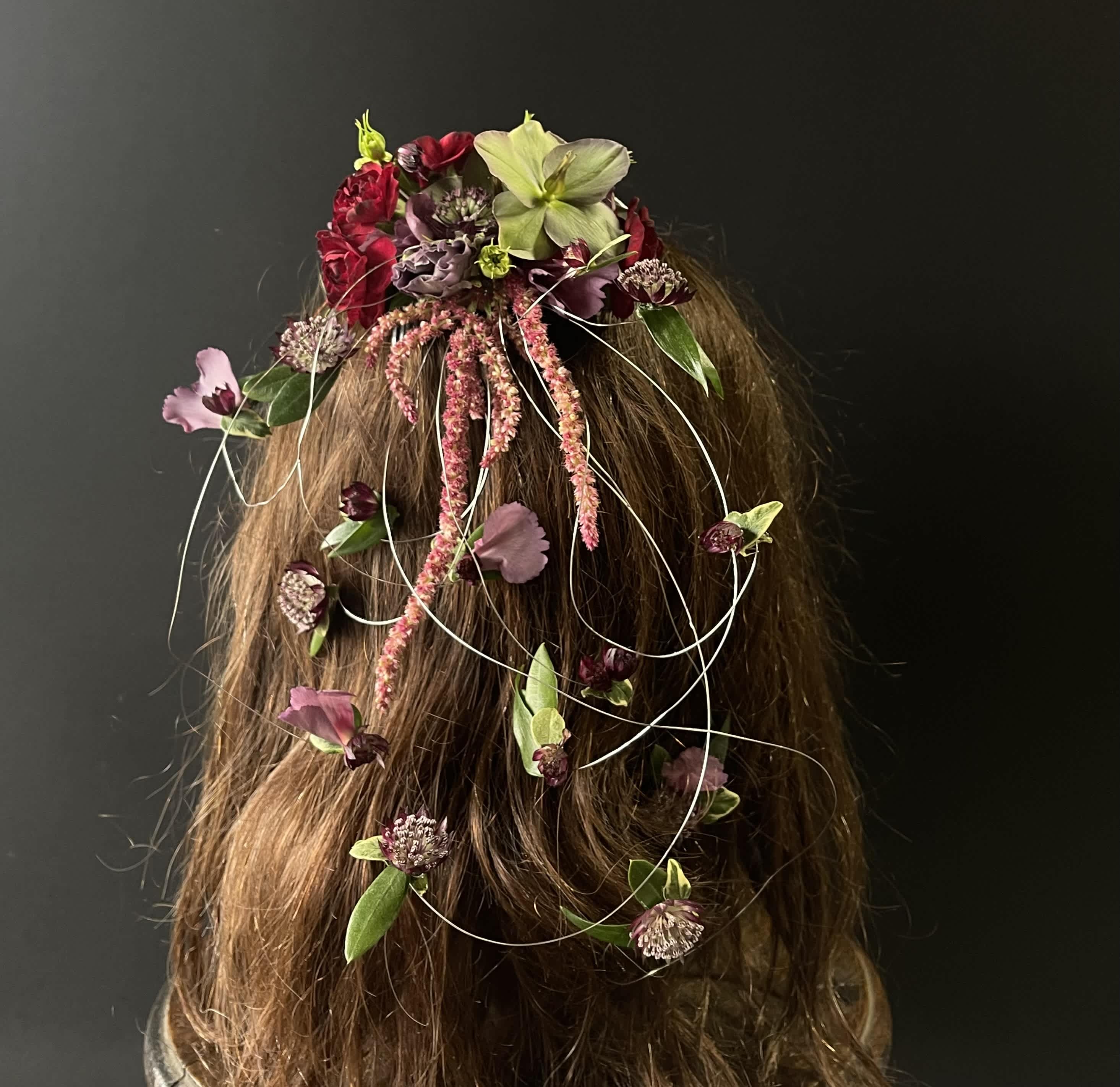Floral hairpiece with red, pink, and green blooms on long hair