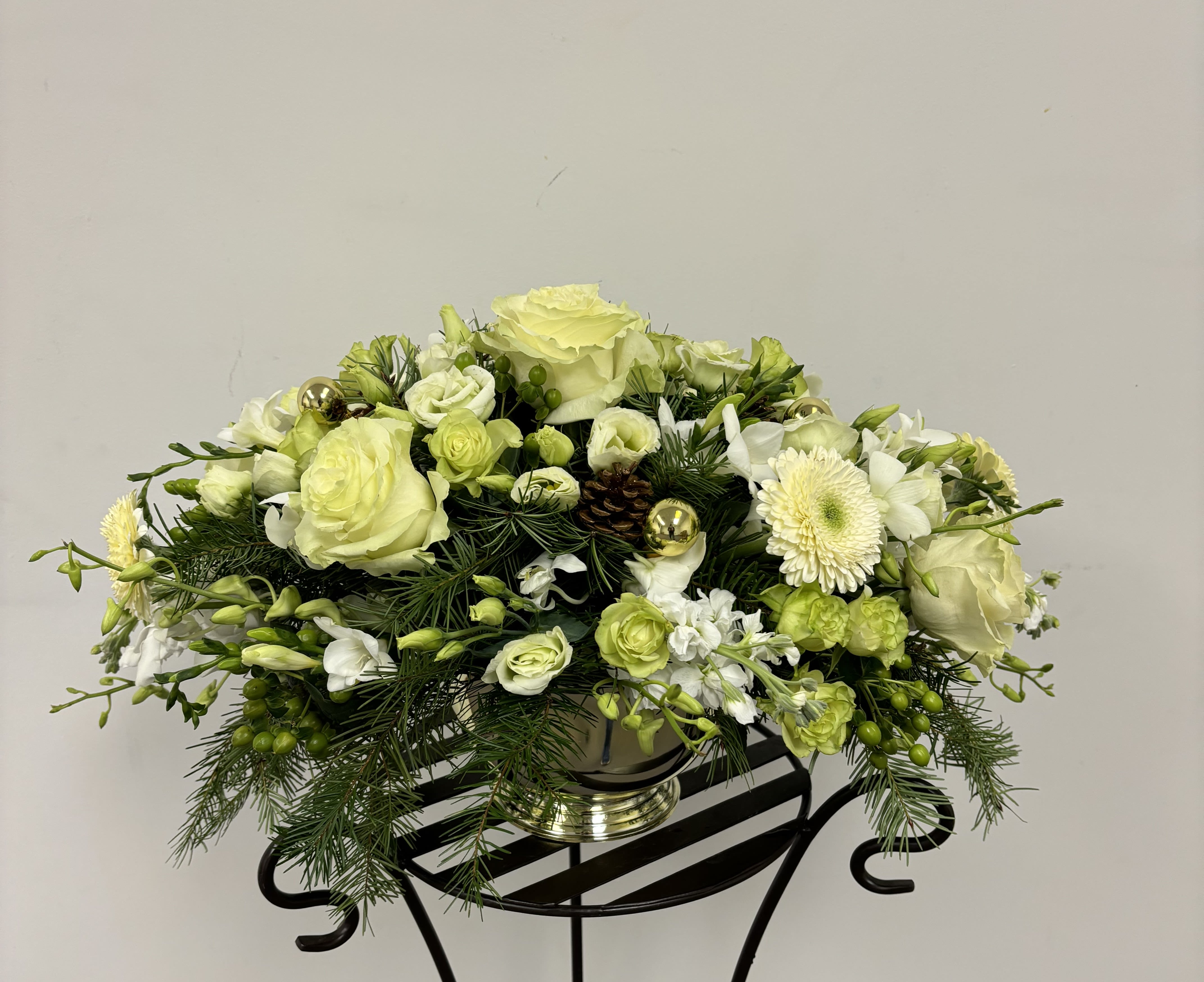Low floral centerpiece with pale green and white blooms in a silver vase