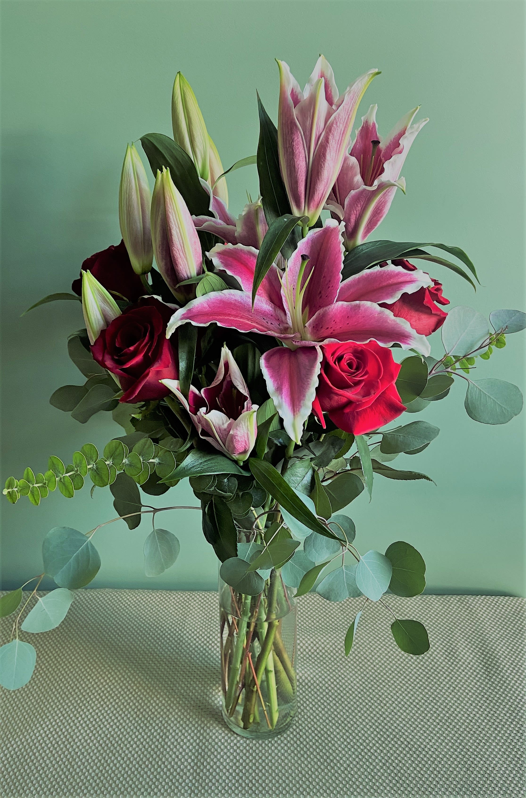 Bouquet of pink lilies and red roses in a clear glass vase