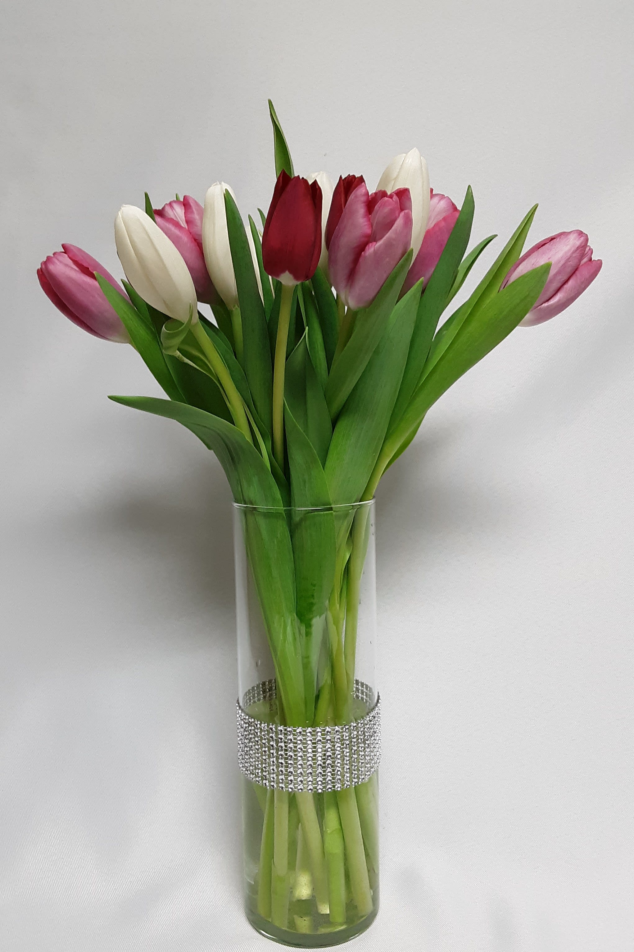 Bouquet of pink, white, and red tulips in a clear glass vase