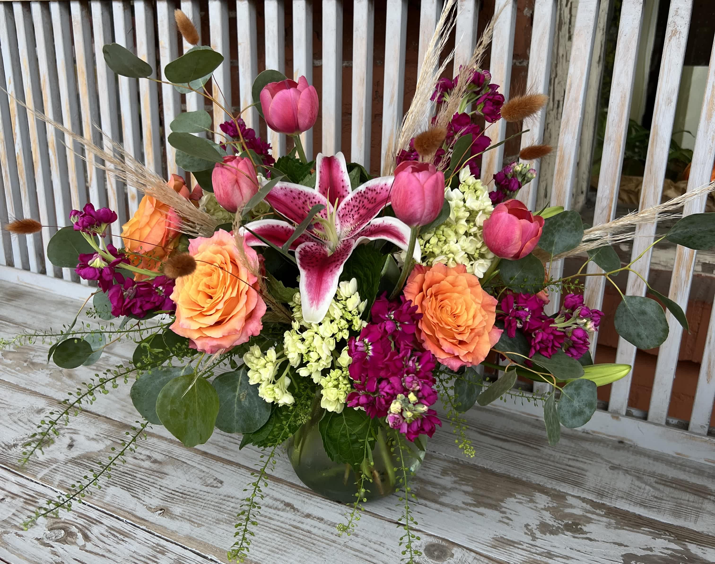 Bouquet of pink lilies, roses, and tulips in a glass vase