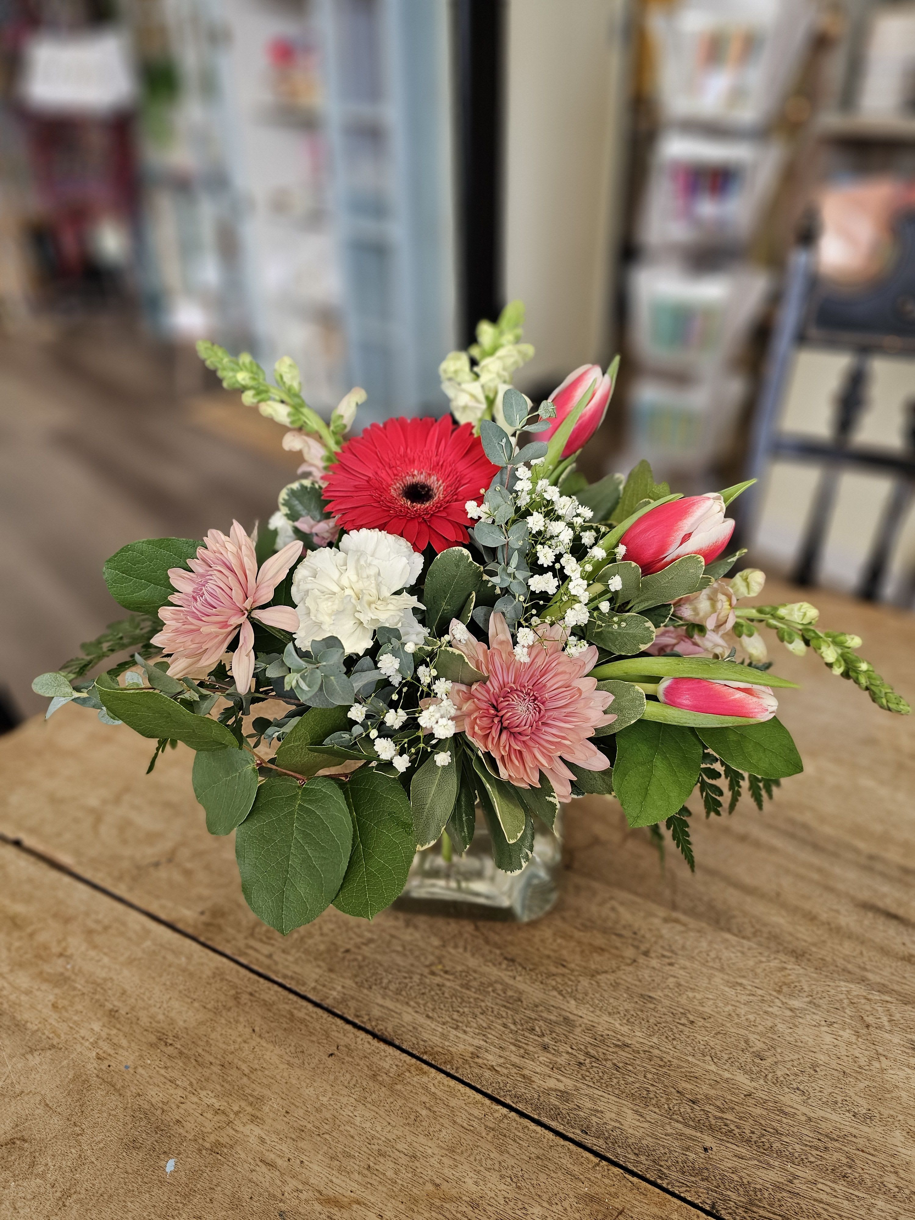 Mixed pink and white flowers arranged in a clear glass vase