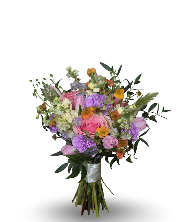 Wild Garden Prom Posy - Loose, hand-tied and effortlessly romantic, this Wild Garden Posy is a pastel event bouquet perfect for a wedding or prom. Pink roses and tulips mingle with purple carnations and small orange daisy-like accents, while airy greenery and slightly trailing stems create a garden-style, slightly cascading silhouette that reads elegant and feminine when carried.  Finished with a white satin ribbon at the base, the bouquet feels polished yet natural-ideal for a bride or attendant who wants a soft, celebratory look. Colors: pink, purple, white, orange, mixed; flowers include roses, tulips, carnations, daisies and mixed seasonal blooms. Bouquet comes in a small vase with minimal water to keep fresh.
