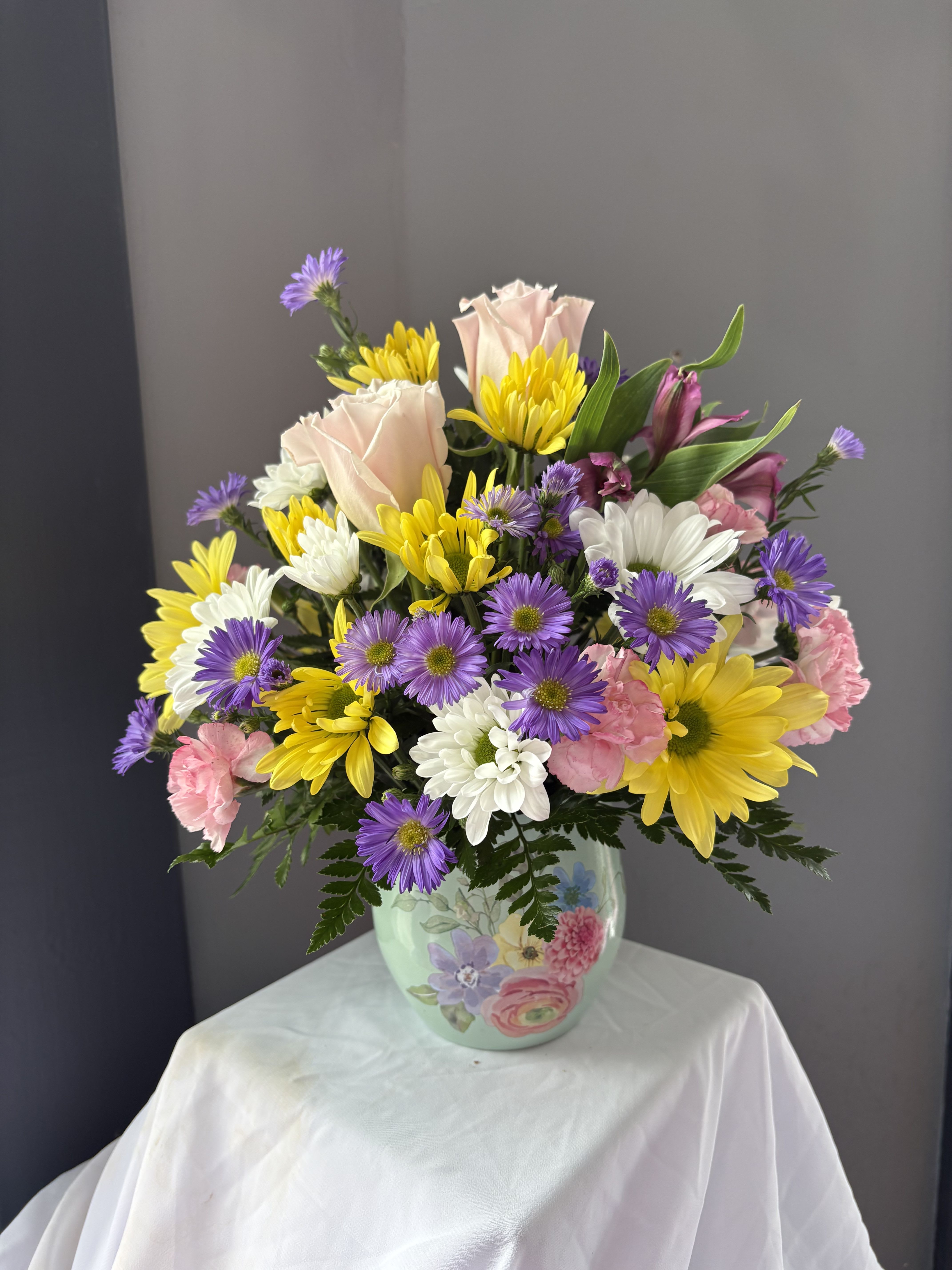 Frazier's Version Watercolor Garden Bouquet - Frazier's Version Watercolor Garden Bouquet is a cheerful Mother's Day flower arrangement of pink roses, daisies, mini carnations, and alstroemeria.   The scale of the arrangement should determine the type of substitution acceptable, but the substitution must be of equal or greater value and must maintain the style and color harmony of the original order.