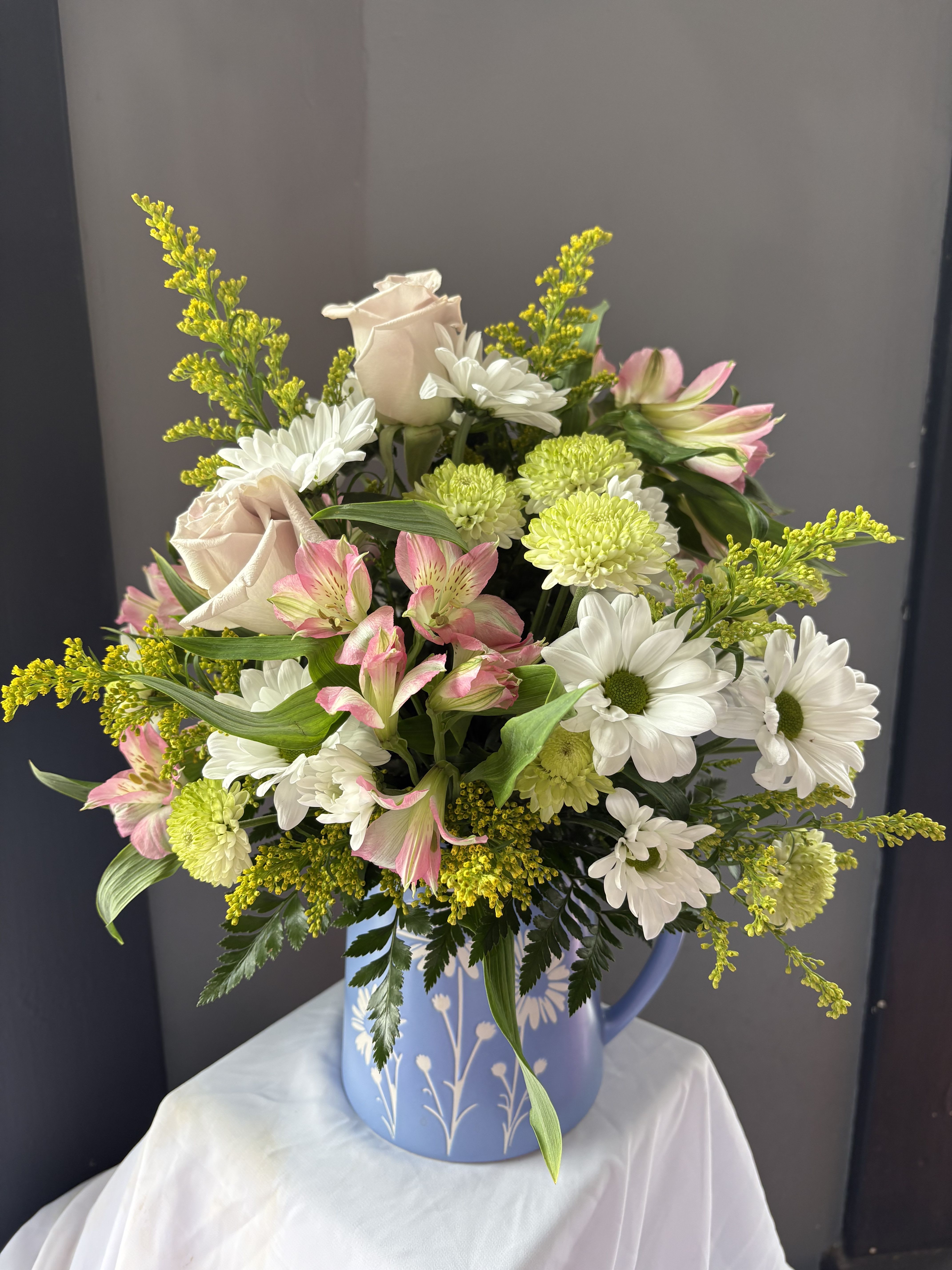 Frazier's Flowers Daisy Dreams Bouquet - Brimming with fresh-picked charm, Frazier's Version Daisy Dreams Bouquet delights with arranged lavender roses, green buttons, pink alstroemeria, white daises, and solidago in a food-safe blue pitcher adorned with a sweet white daisy design.