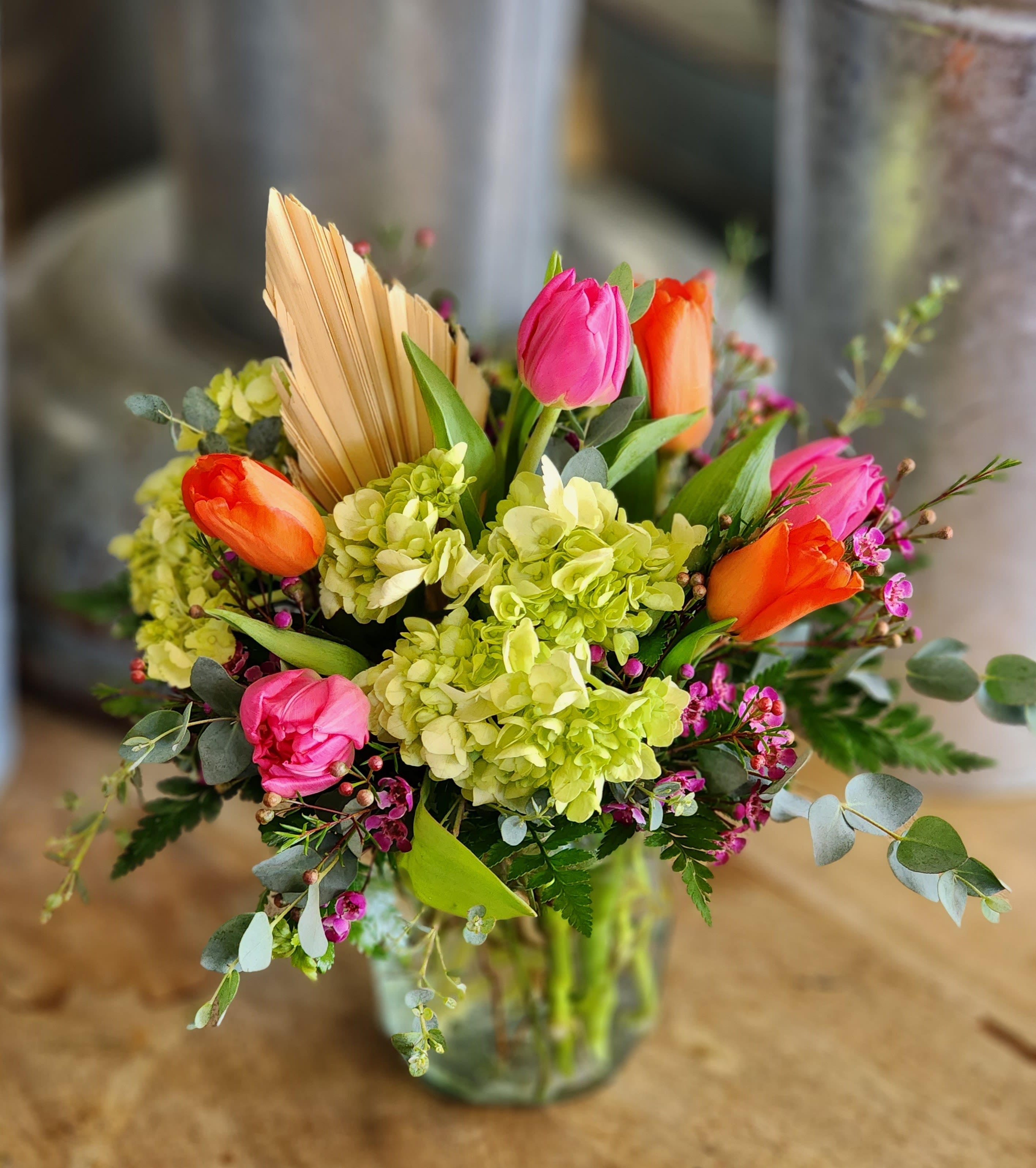 Bouquet of pink and orange tulips with green hydrangeas in a glass vase